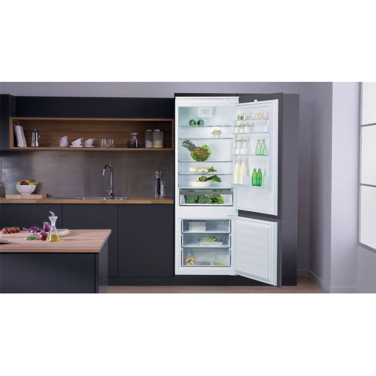 Cucina moderna con frigorifero aperto che mostra cibo e ripiani. Piano di lavoro in legno con utensili.