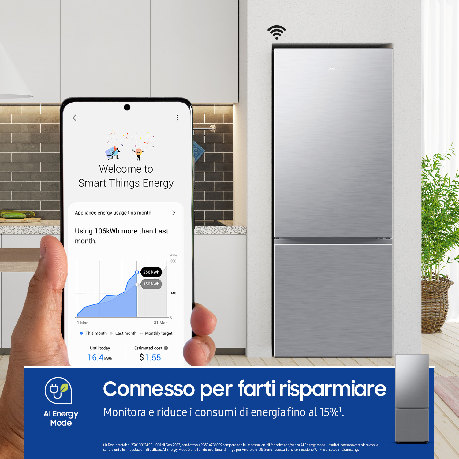 Una persona tiene in mano un telefono che mostra l'uso di energia accanto a un frigorifero d'argento.