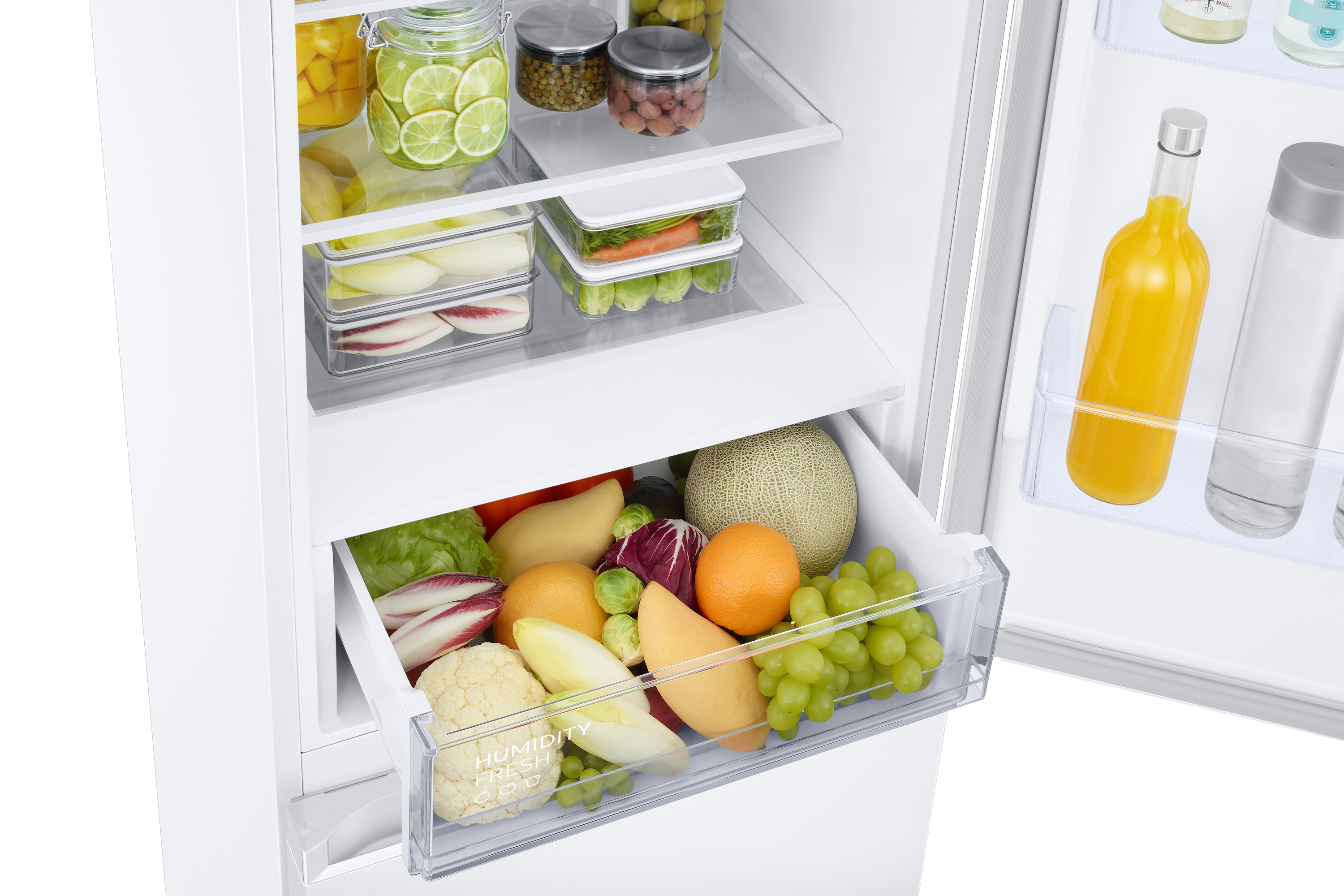 Refrigerator drawer filled with fruits and vegetables. Includes cauliflower, grapes, and oranges.
