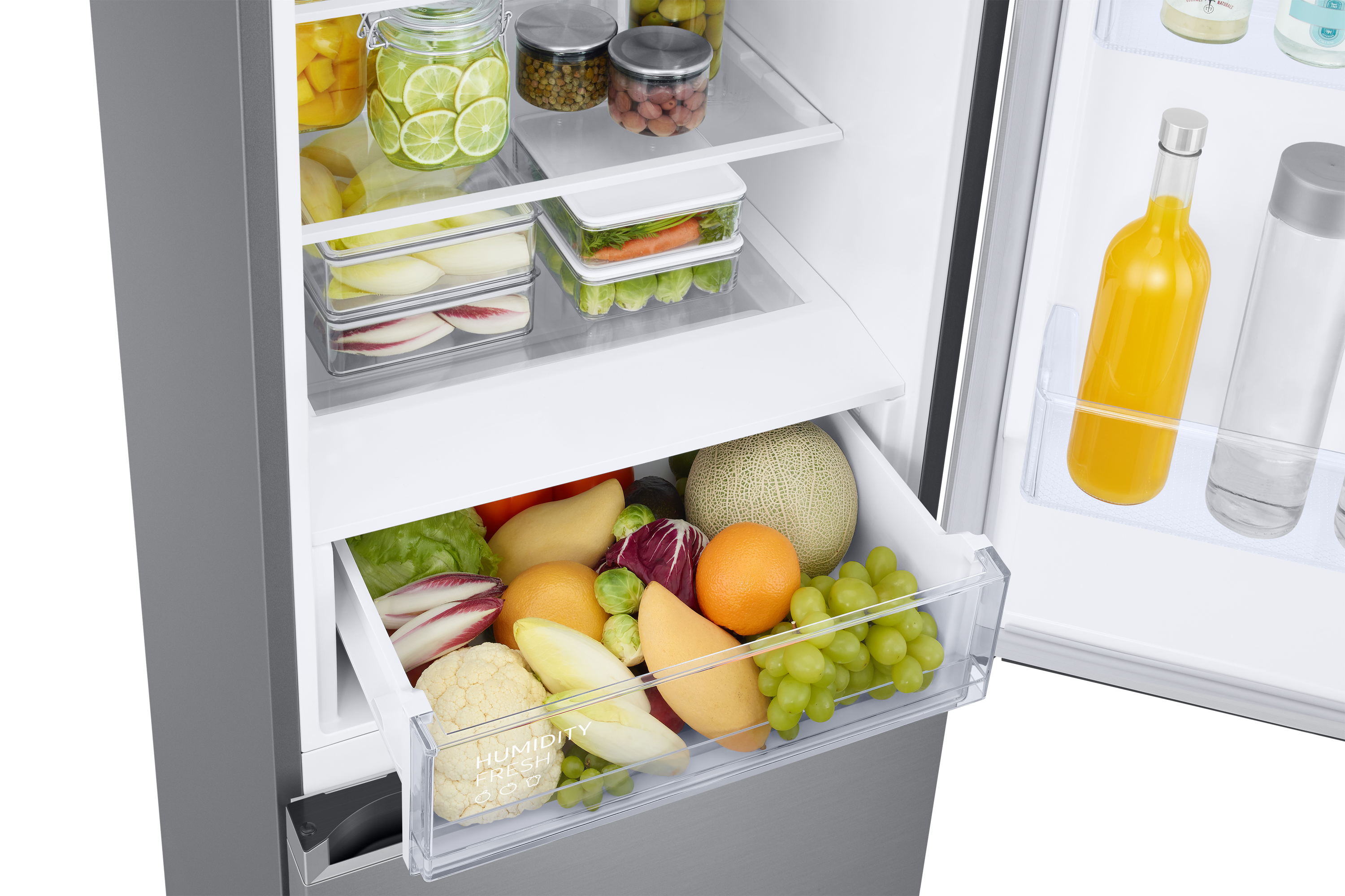 Interior de refrigerador con estantes, cajón de productos con frutas y verduras y varios tarros.