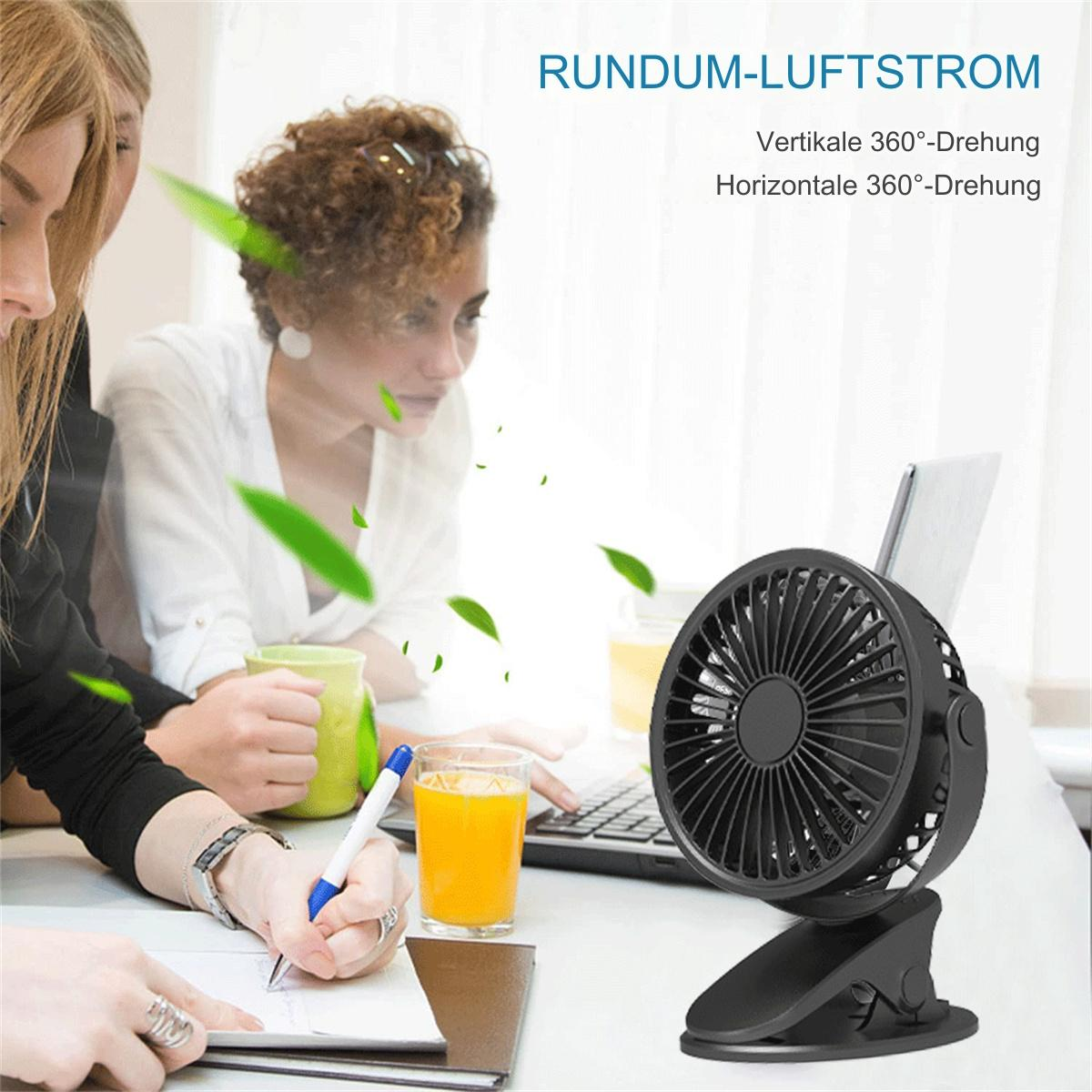 Ein schwarzer Schreibtischventilator mit Clipfuß, Tablet und Glas Saft. Personen im Hintergrund.