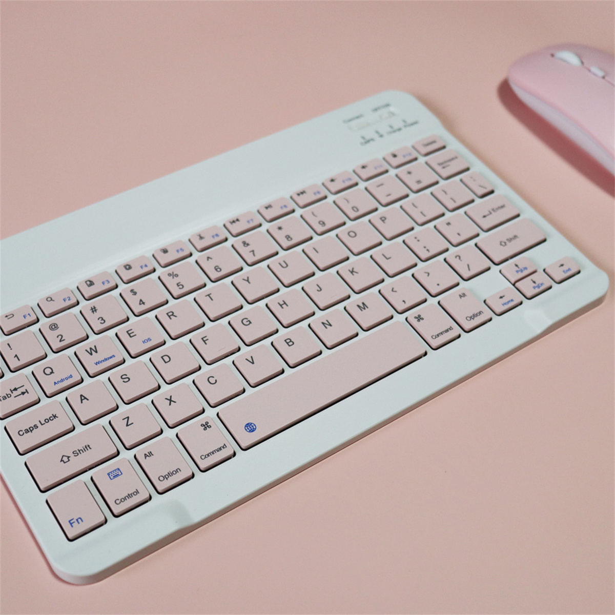 Weiße Tastatur mit rosa Tasten und rosa Maus. Auf einer rosa Oberfläche.