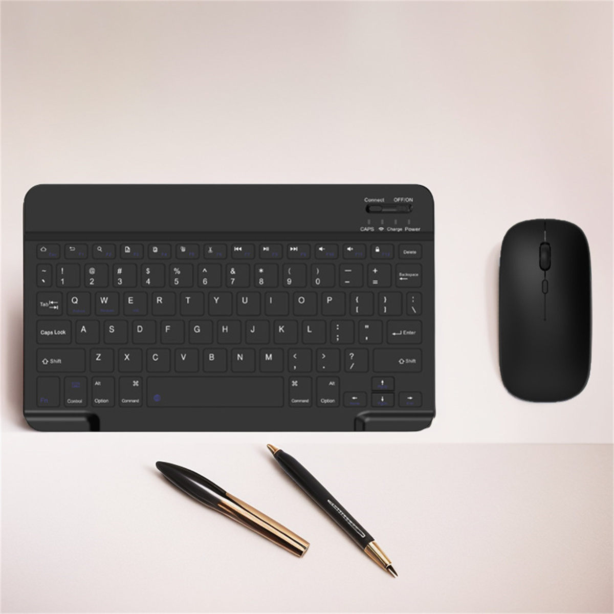 Schwarze Tastatur und Maus auf weißer Oberfläche, mit zwei Stiften.