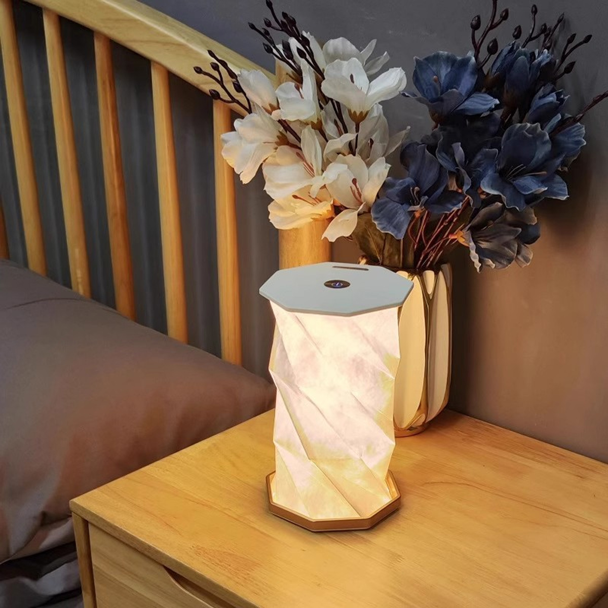 Nachttisch mit Lampe, Blumenvase. Lampe ist weiß und leuchtet. Warme Beleuchtung.