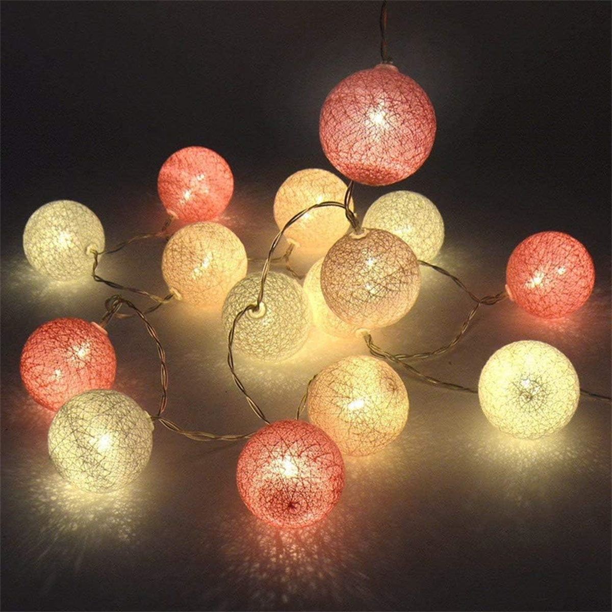 Lichterkette mit mehreren leuchtenden, runden, rosa und weißen Kugeln.