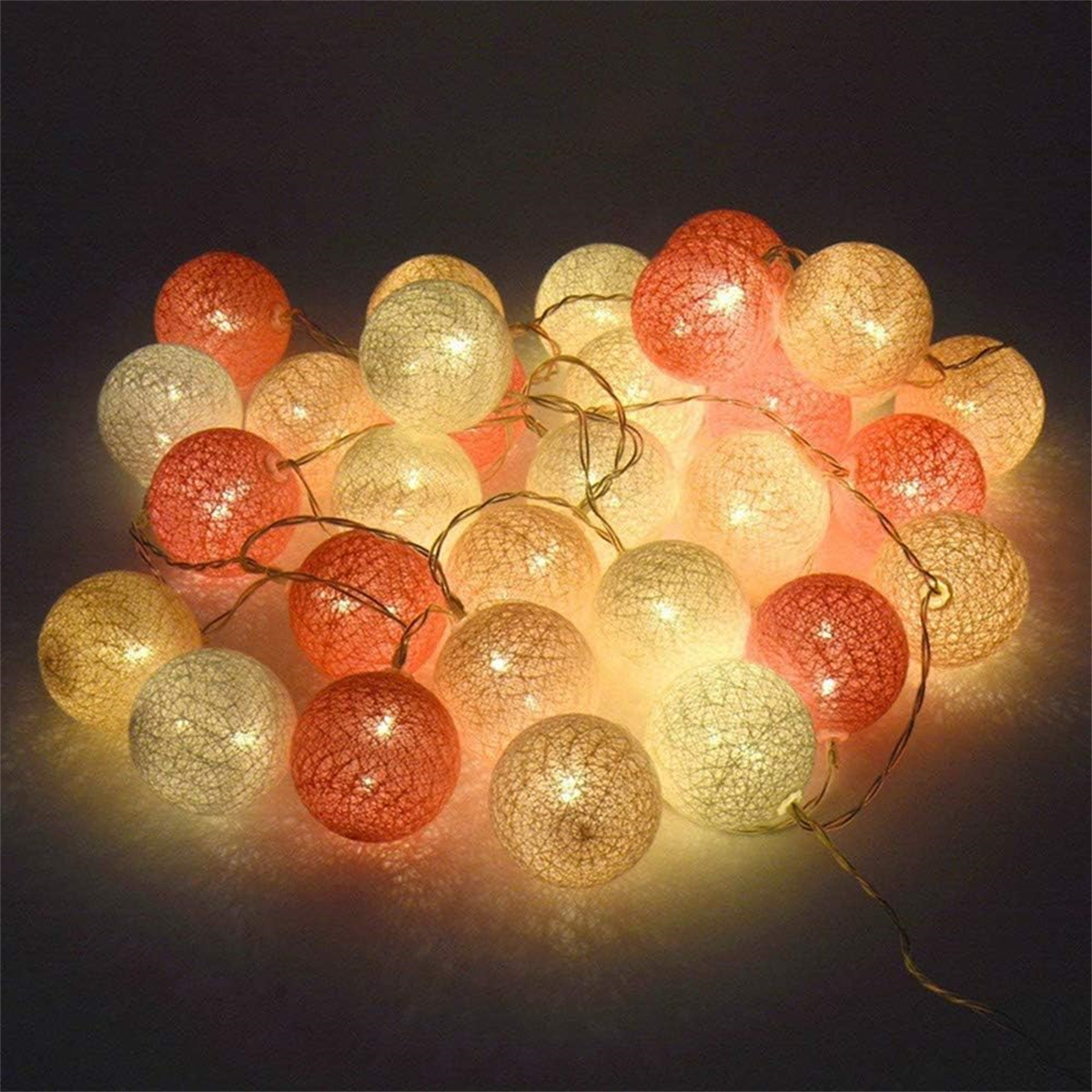 Kette aus leuchtenden, kugelförmigen Lichtern, Mischung aus Orange und Weiß, auf dunkler Oberfläche.