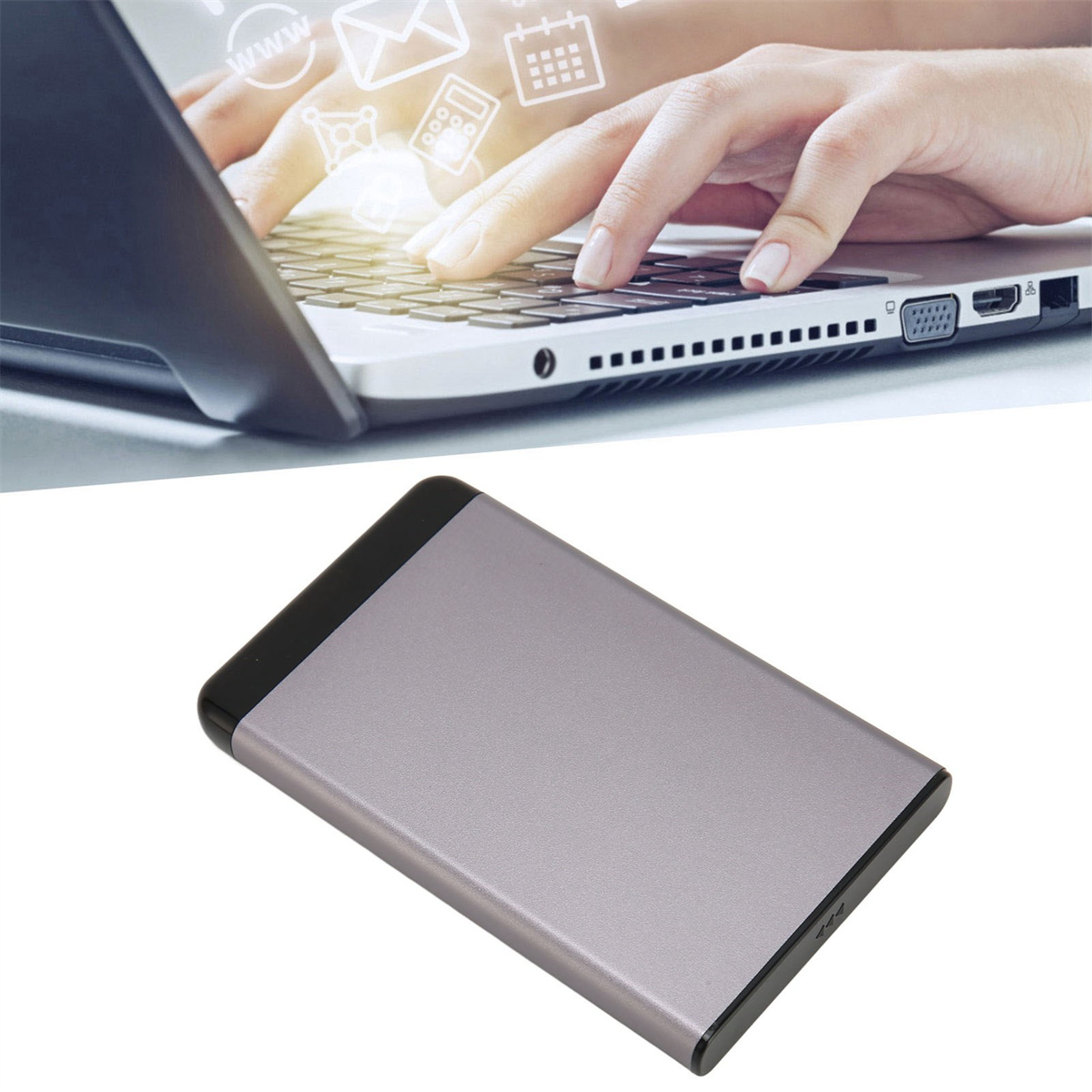 Eine Laptop-Tastatur, auf der eine Hand tippt, und eine silberne externe Festplatte.