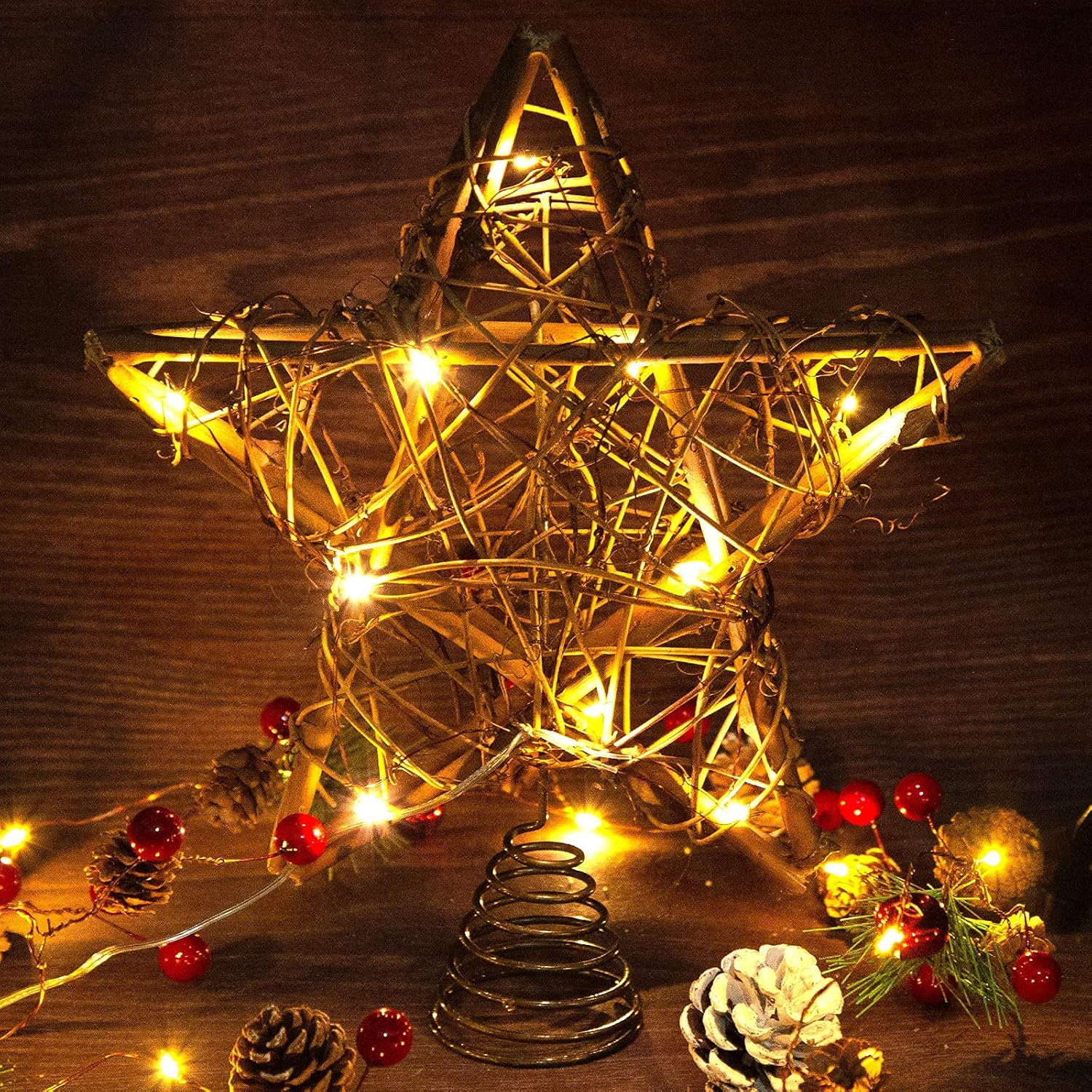 Sternförmiger Weihnachtsschmuck. Lichter sind an. Tannenzapfen und rote Beeren auf dem Tisch.