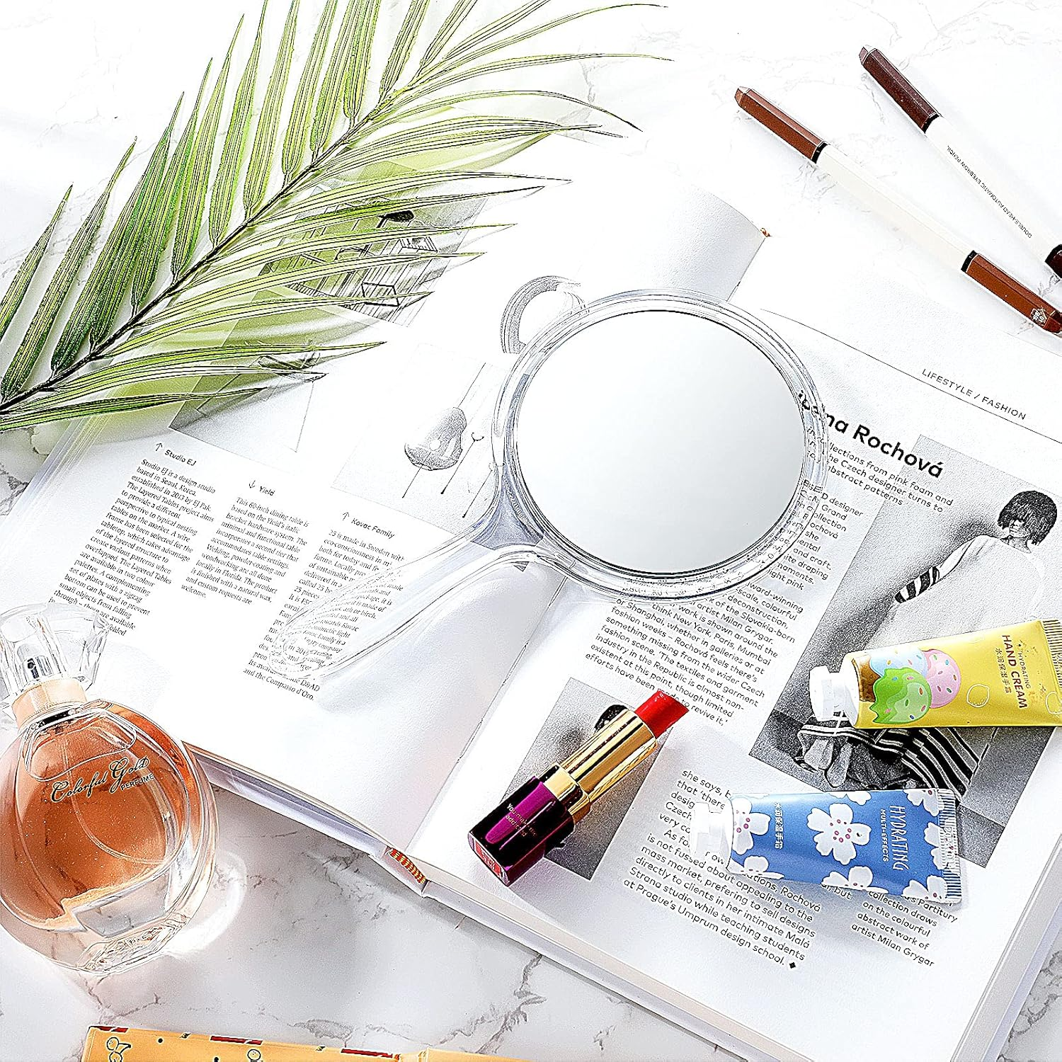 Geöffnetes Magazin mit Parfüm, Lippenstift, Handcremes und einer Lupe.