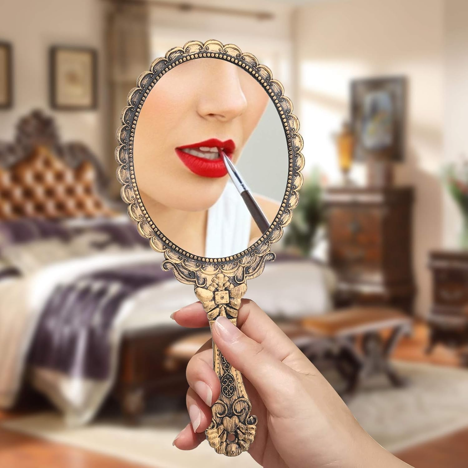 Die Hand einer Person hält einen goldgerahmten ovalen Spiegel. Der Spiegel zeigt eine Frau, die roten Lippenstift aufträgt.