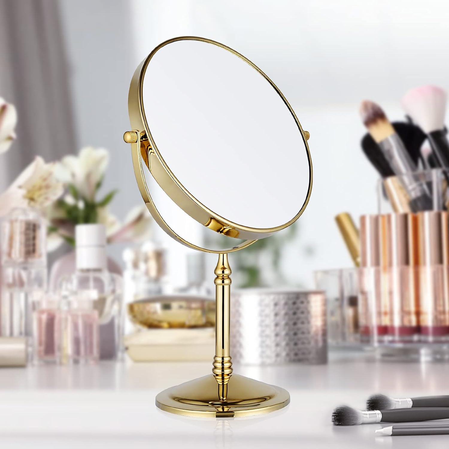 Ein goldener, runder Schminkspiegel steht auf einem weißen Tisch, mit verschwommenem Hintergrund.