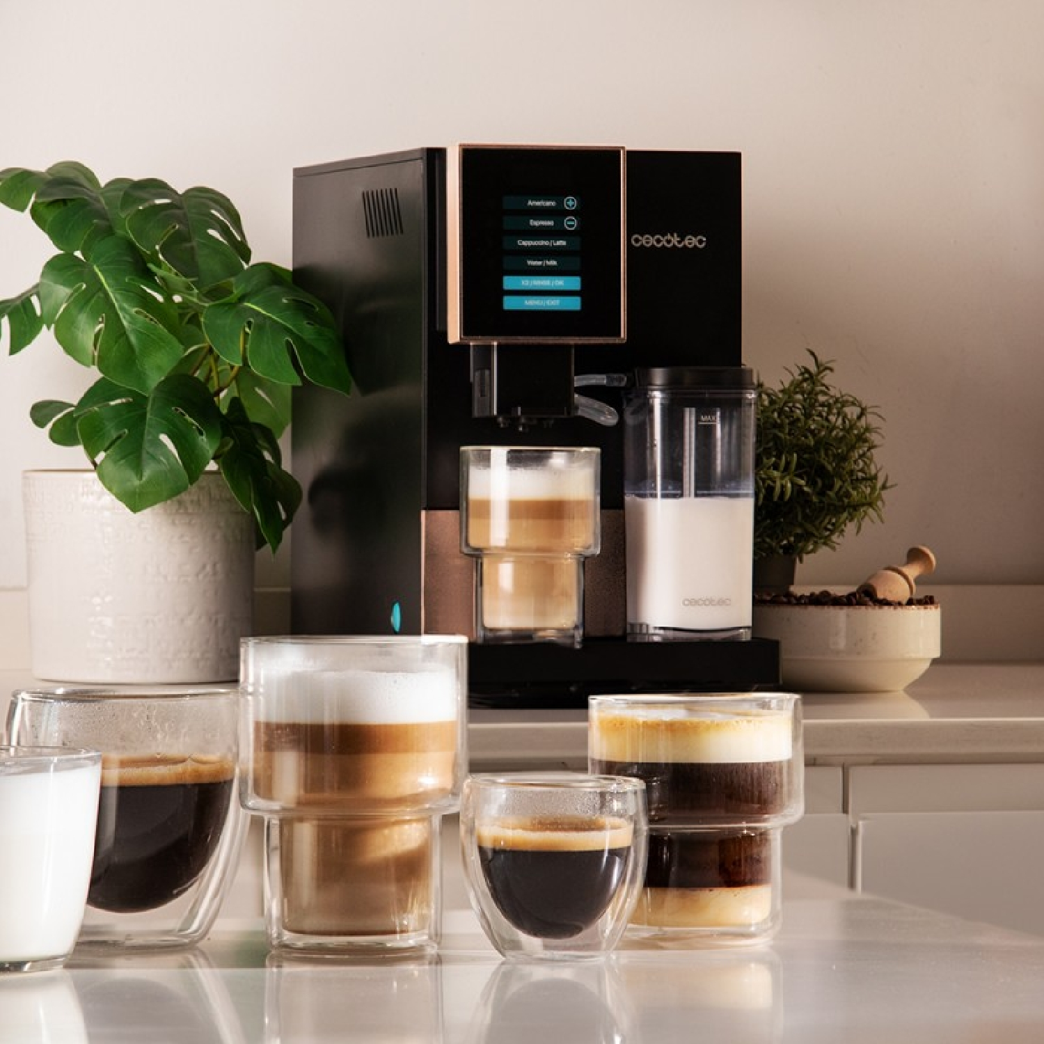 Macchina per caffè espresso con tazze, latte e una pianta. Ha pulsanti per diversi tipi di caffè.