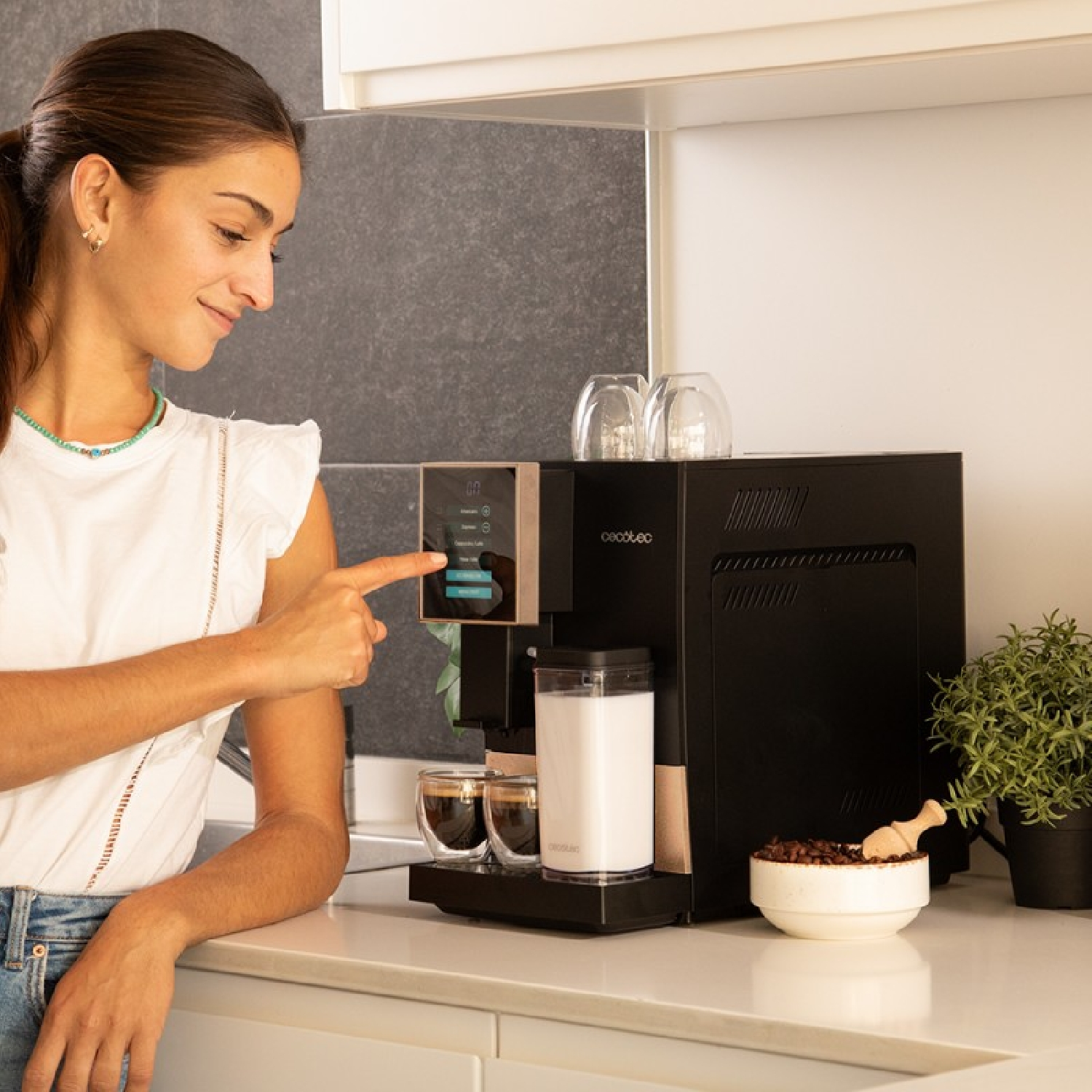 Donna usa macchina da caffè, con tazze, latte e chicchi sul bancone.