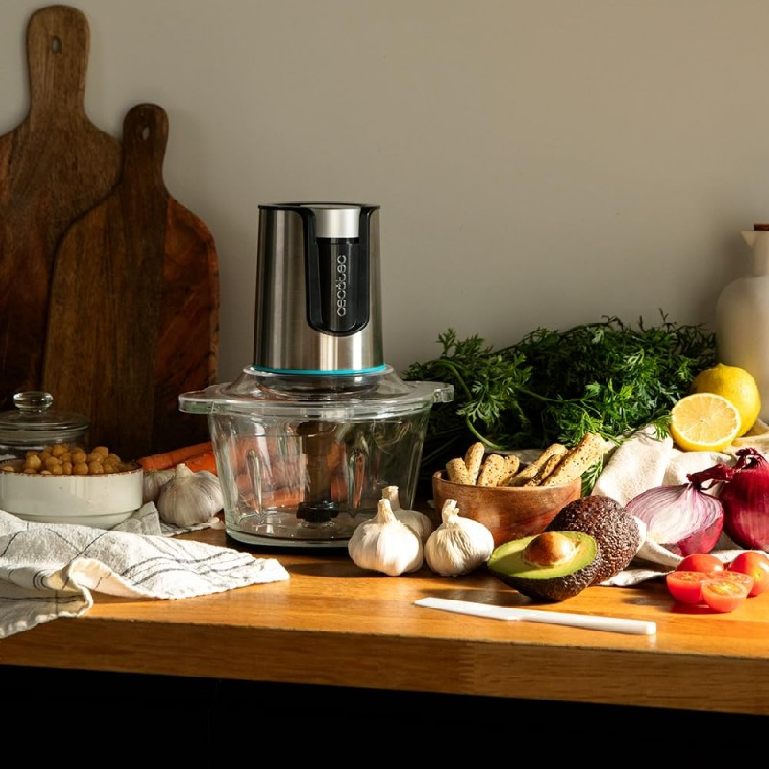 Un piano di lavoro della cucina con un robot da cucina, ingredienti come aglio e verdure.