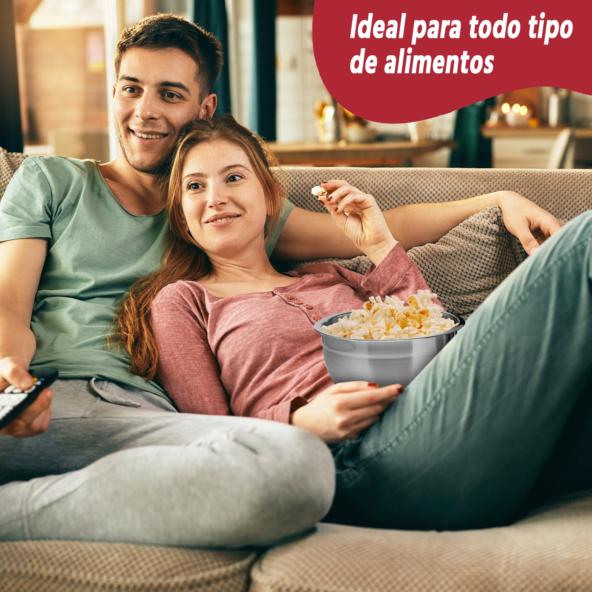 Una pareja sentada en un sofá, comiendo palomitas de maíz y viendo la televisión.