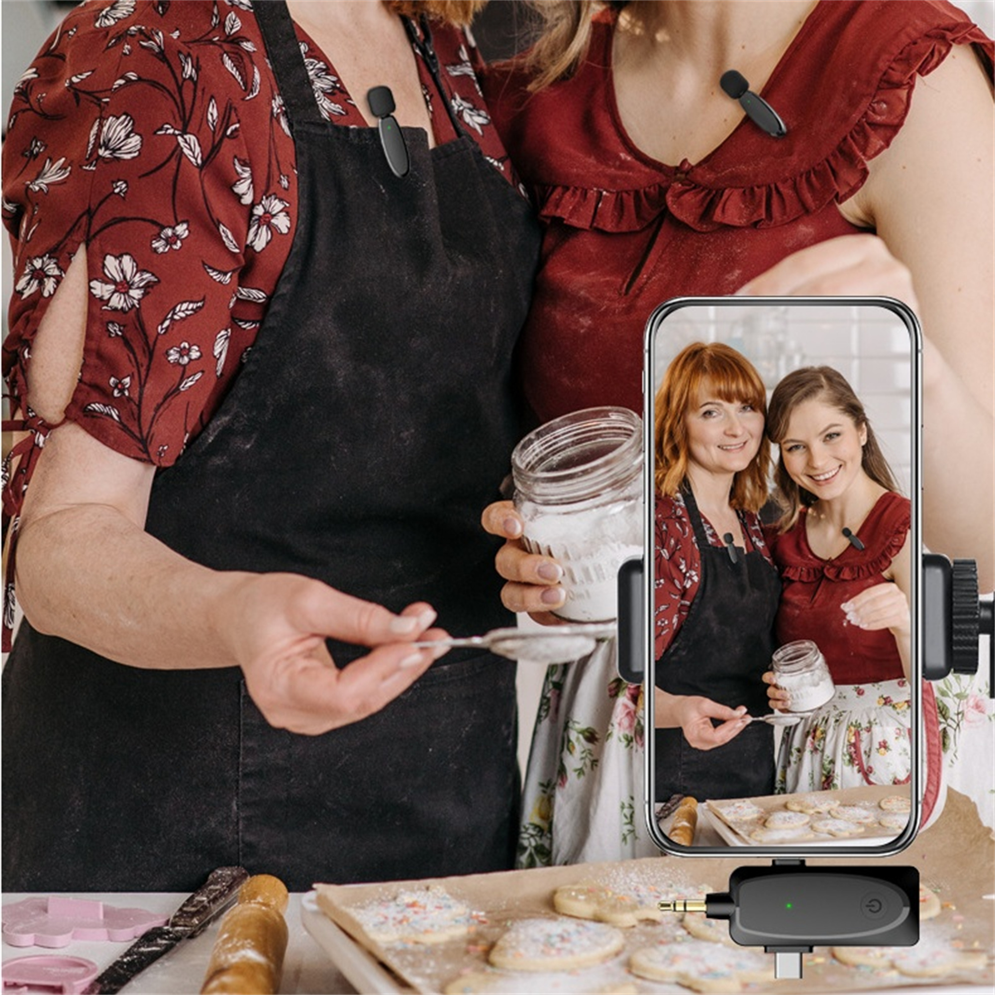 Zwei Frauen mit Mikrofonen, eine hält ein Glas, die andere zeigt sie auf dem Telefon.
