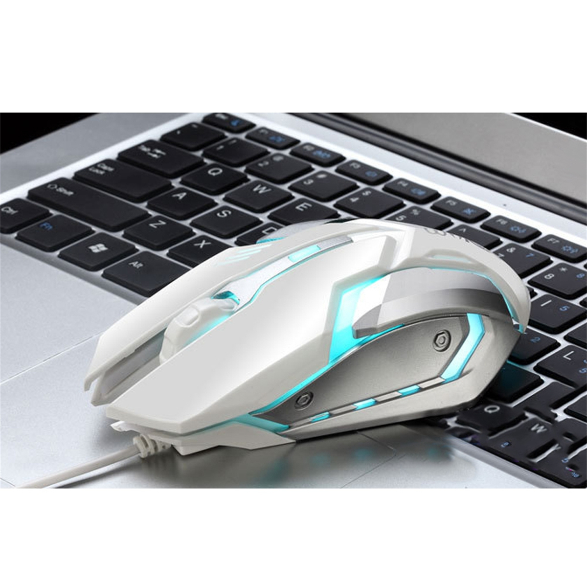 Weiße Maus auf einer Laptop-Tastatur. Die Maus hat blaue Lichter. Sie befindet sich auf einer metallischen Oberfläche.