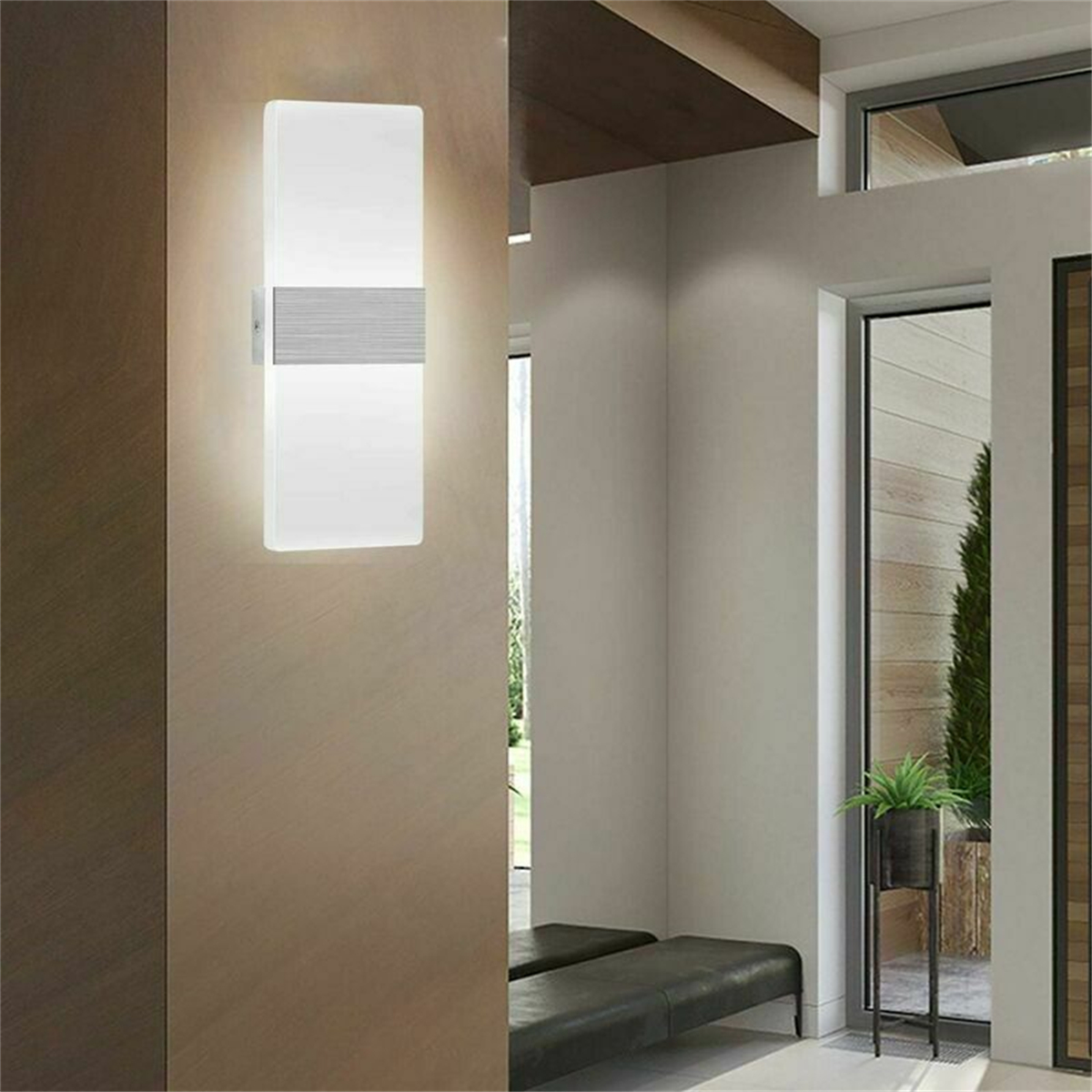 Eine moderne, rechteckige Wandleuchte mit Silberstreifen, montiert an einer Wand neben einer Tür.