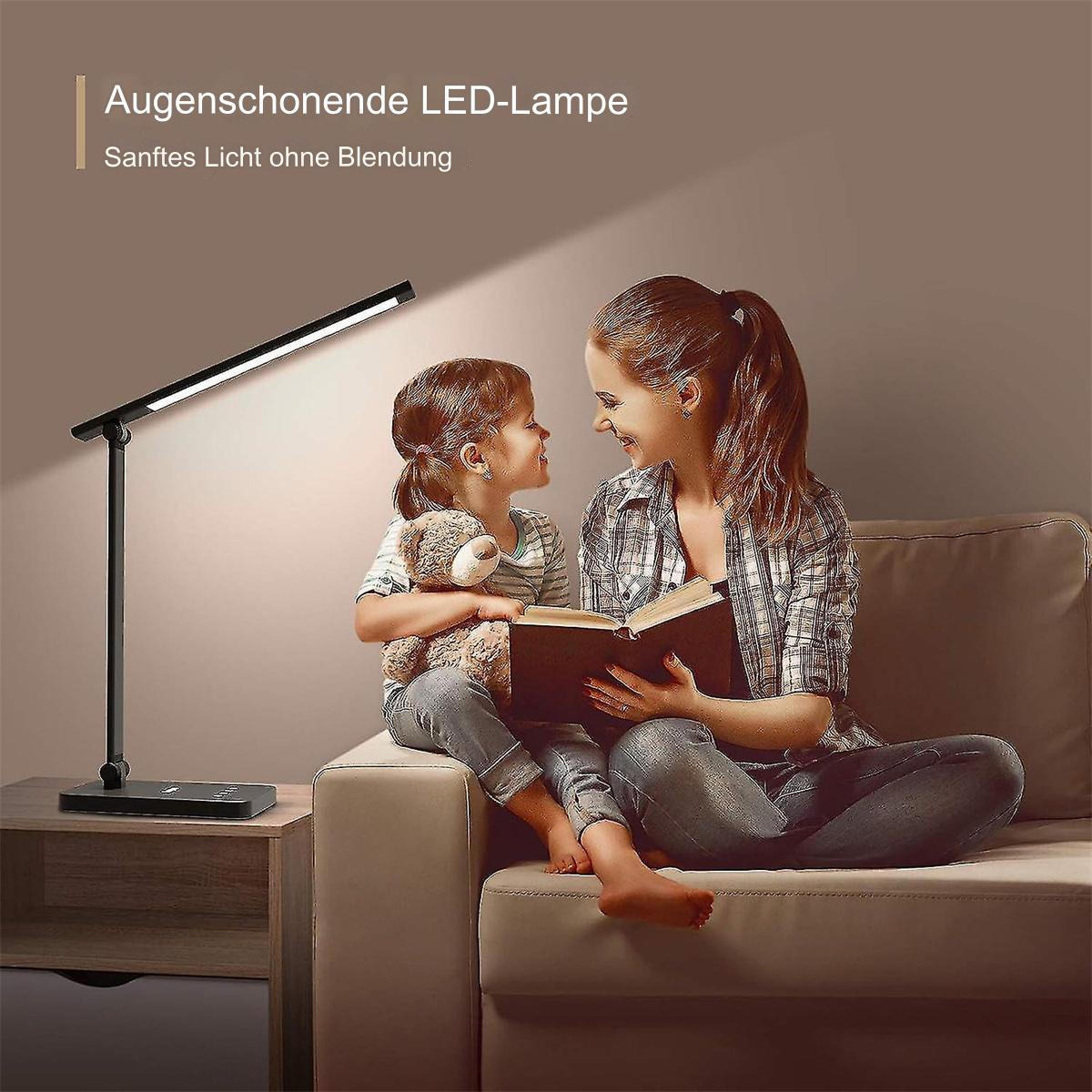 Mutter und Kind sitzen auf einem Sofa und lesen unter einer schwarzen Schreibtischlampe ein Buch.