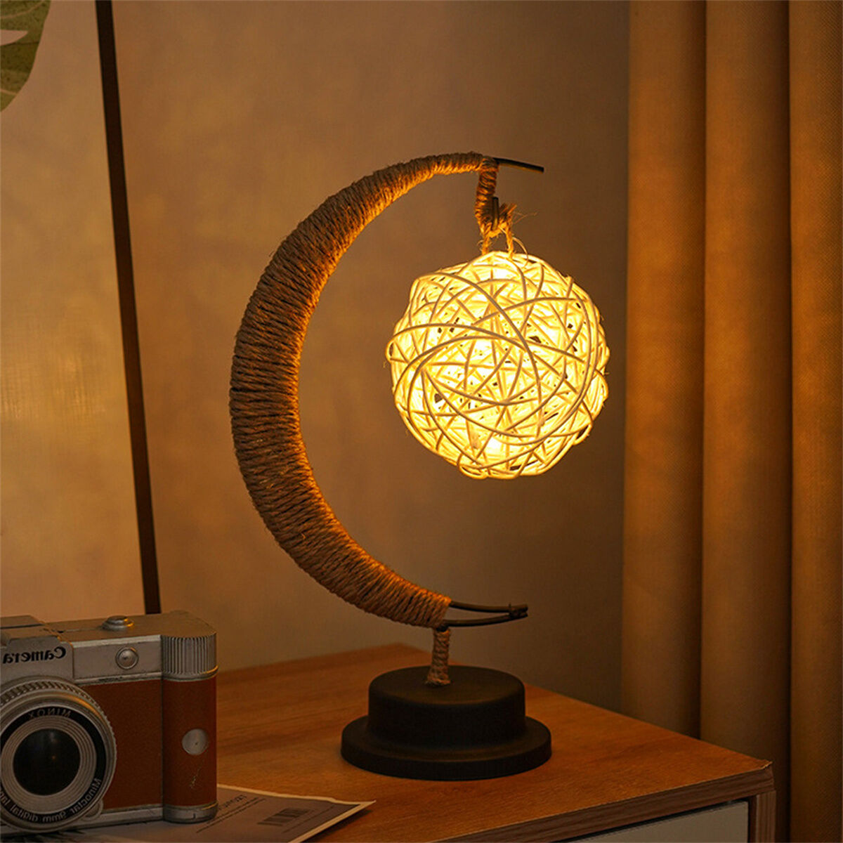 Eine dekorative Lampe mit halbmondförmigem Sockel und kugelförmiger Lichtquelle.