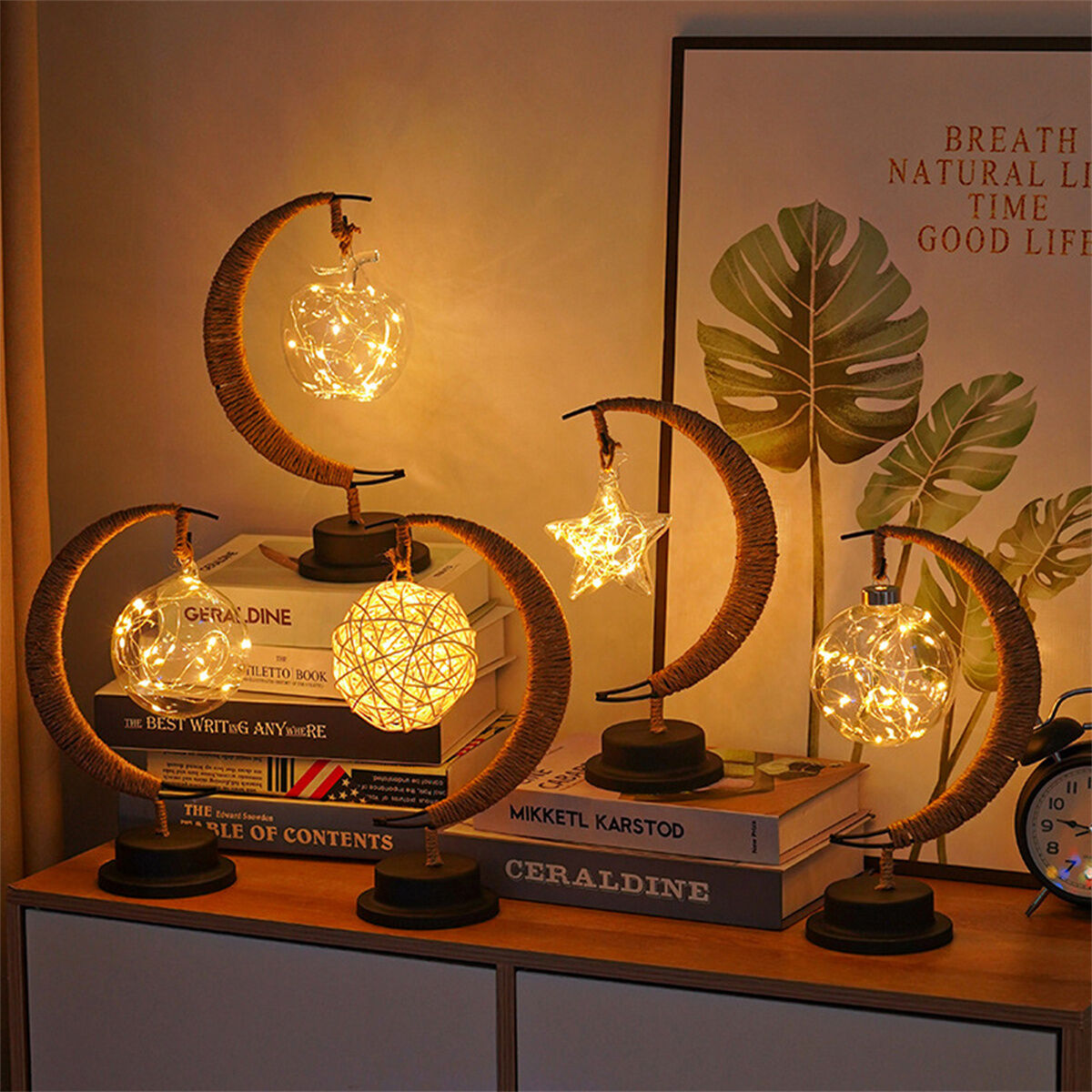 Eine Ansammlung dekorativer Lampen auf einer Kommode. Die Lampen haben Mond- und Sterndesigns und beleuchten die Szene mit warmem Licht.