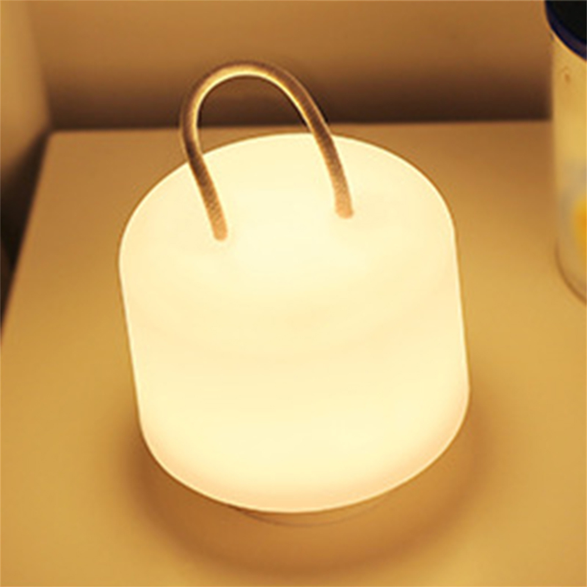 Weiß leuchtende Lampe mit Griff auf einer hellen Oberfläche.