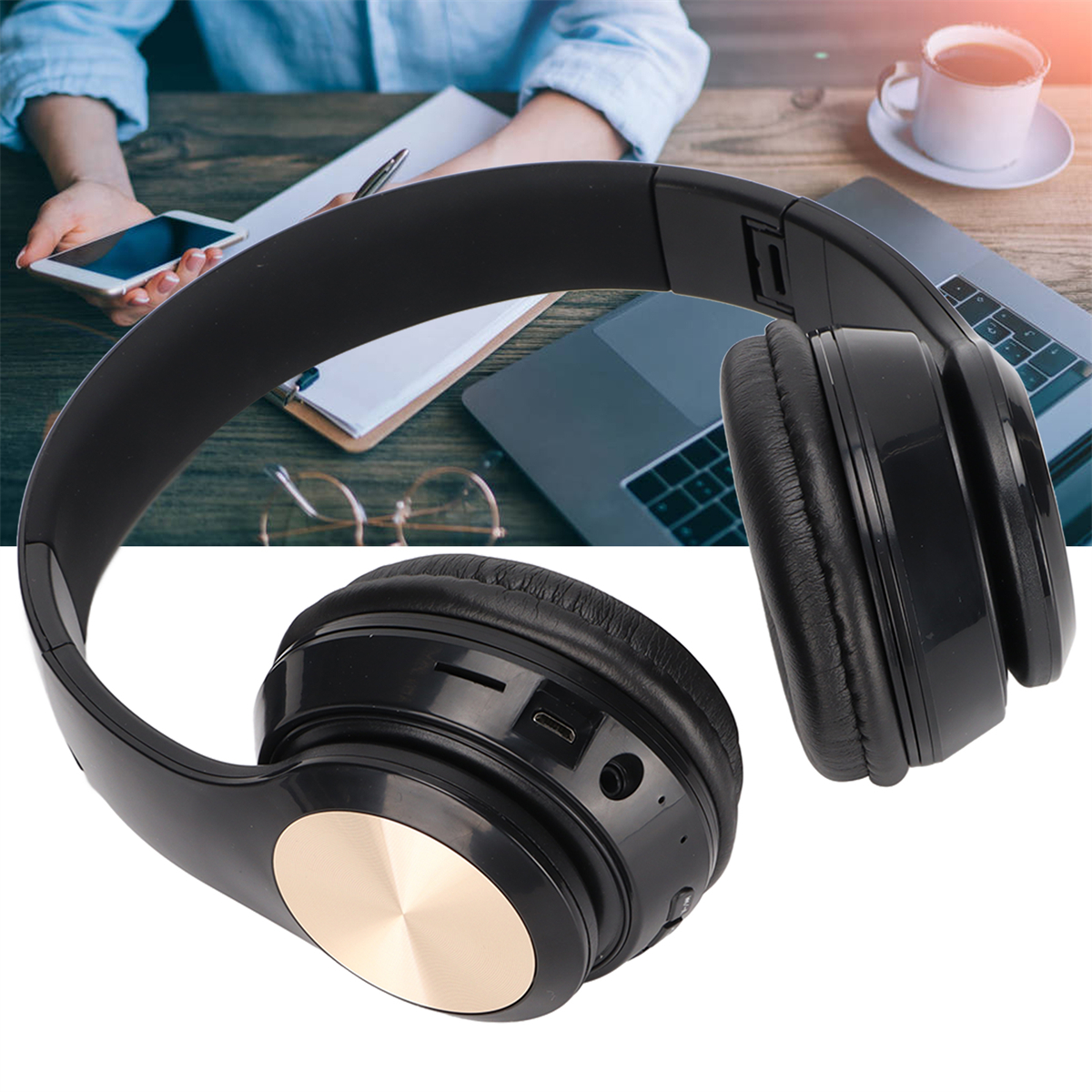 Schwarze Kopfhörer mit goldenen Akzenten auf einem Schreibtisch. Ein Telefon, Laptop und Kaffeetasse sind ebenfalls sichtbar.
