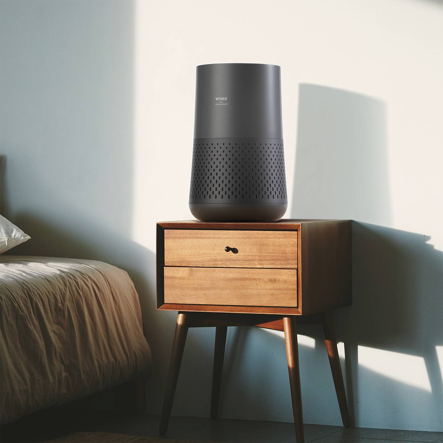 Purificatore d'aria nero su comodino marrone in camera da letto.