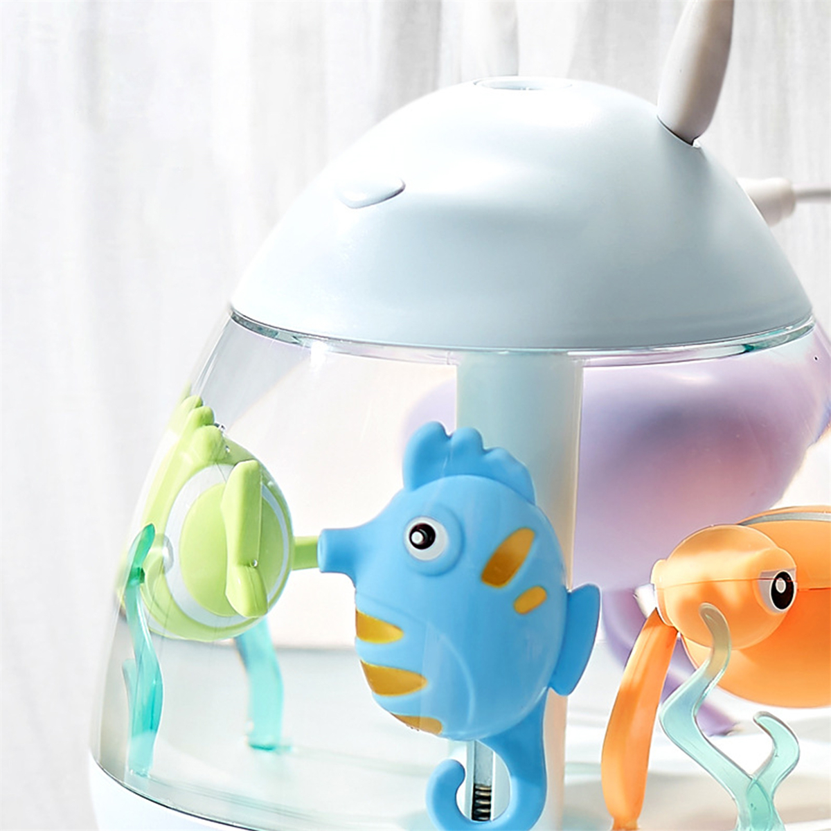Ein Spielzeug-Aquarium mit blauen, grünen und orangen Fischen. Es ist eine Unterwasserszene.