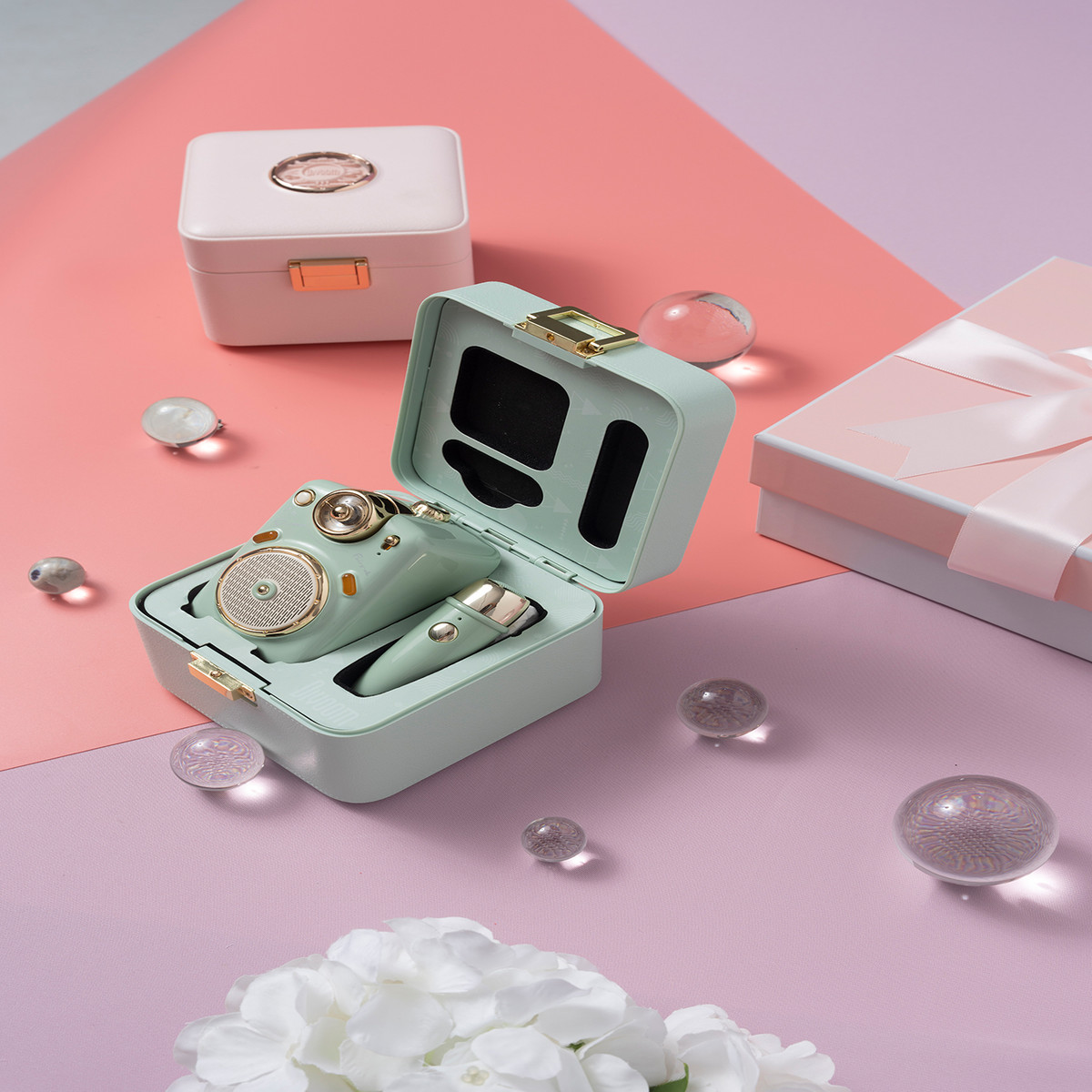 Miętowy zestaw kosmetyczny w pudełku, z lusterkiem, głośnikami i małą buteleczką, na różowej powierzchni.