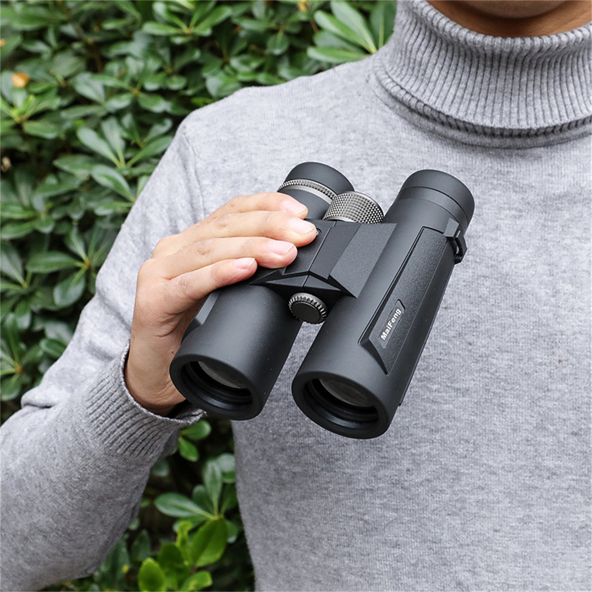 Eine Person hält ein schwarzes Fernglas. Das Fernglas ist auf etwas außerhalb der Kamera gerichtet.