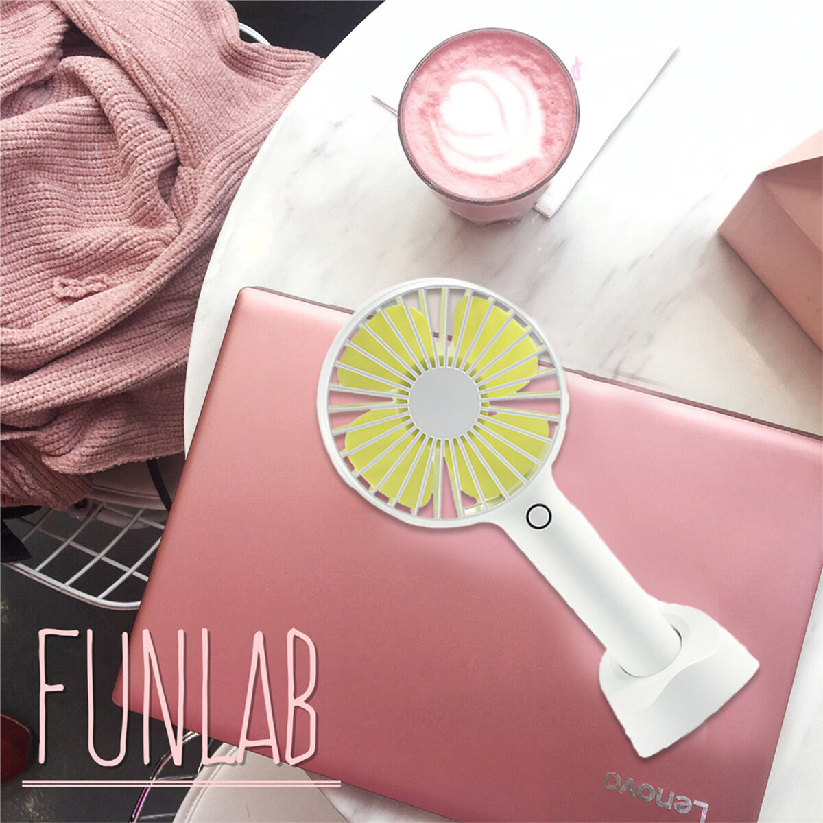 Rosa Laptop mit weißem Handventilator und einem rosa Getränk auf einem Tisch. Funlab Text ist auf dem Laptop.