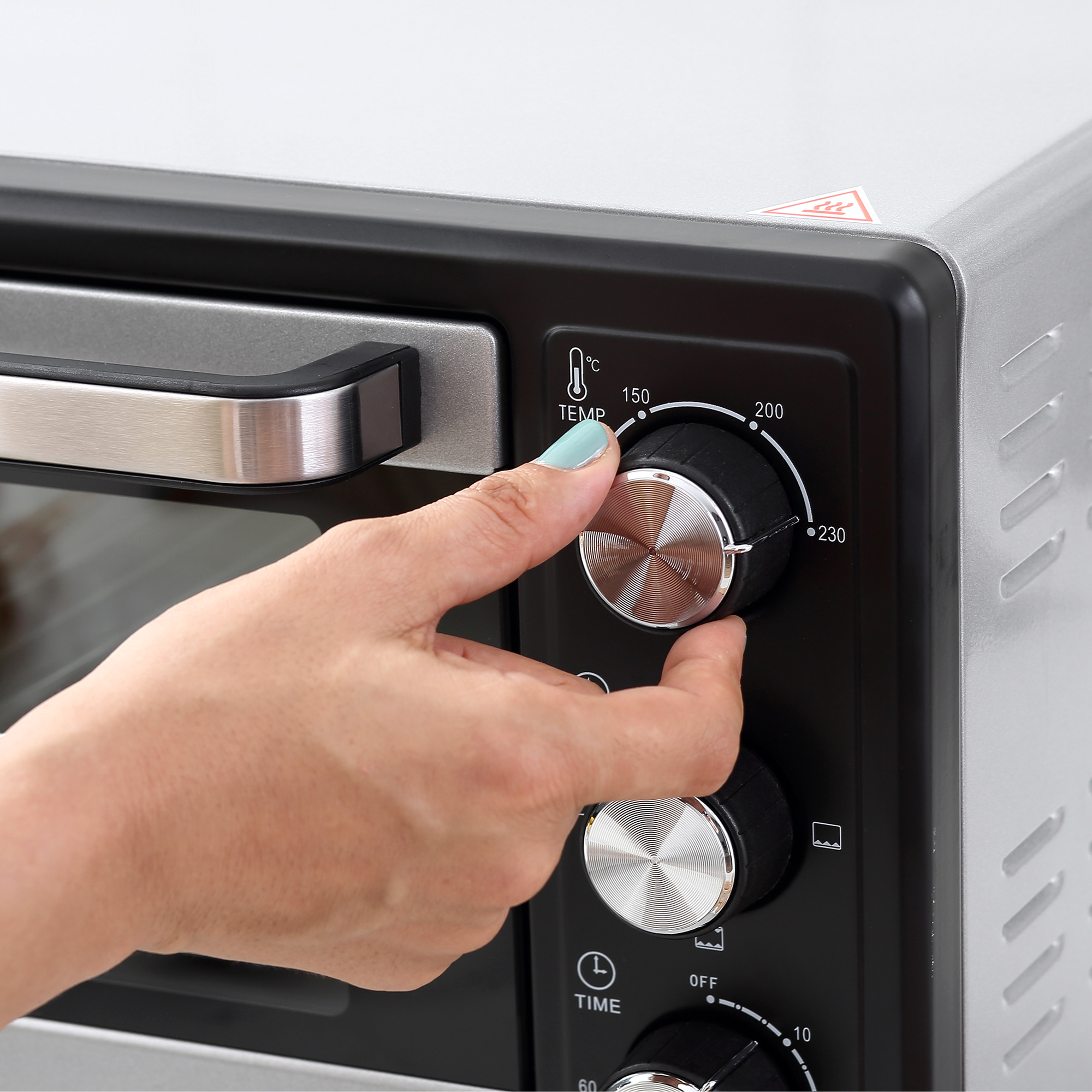 Una mano ajustando el dial de temperatura de un horno.