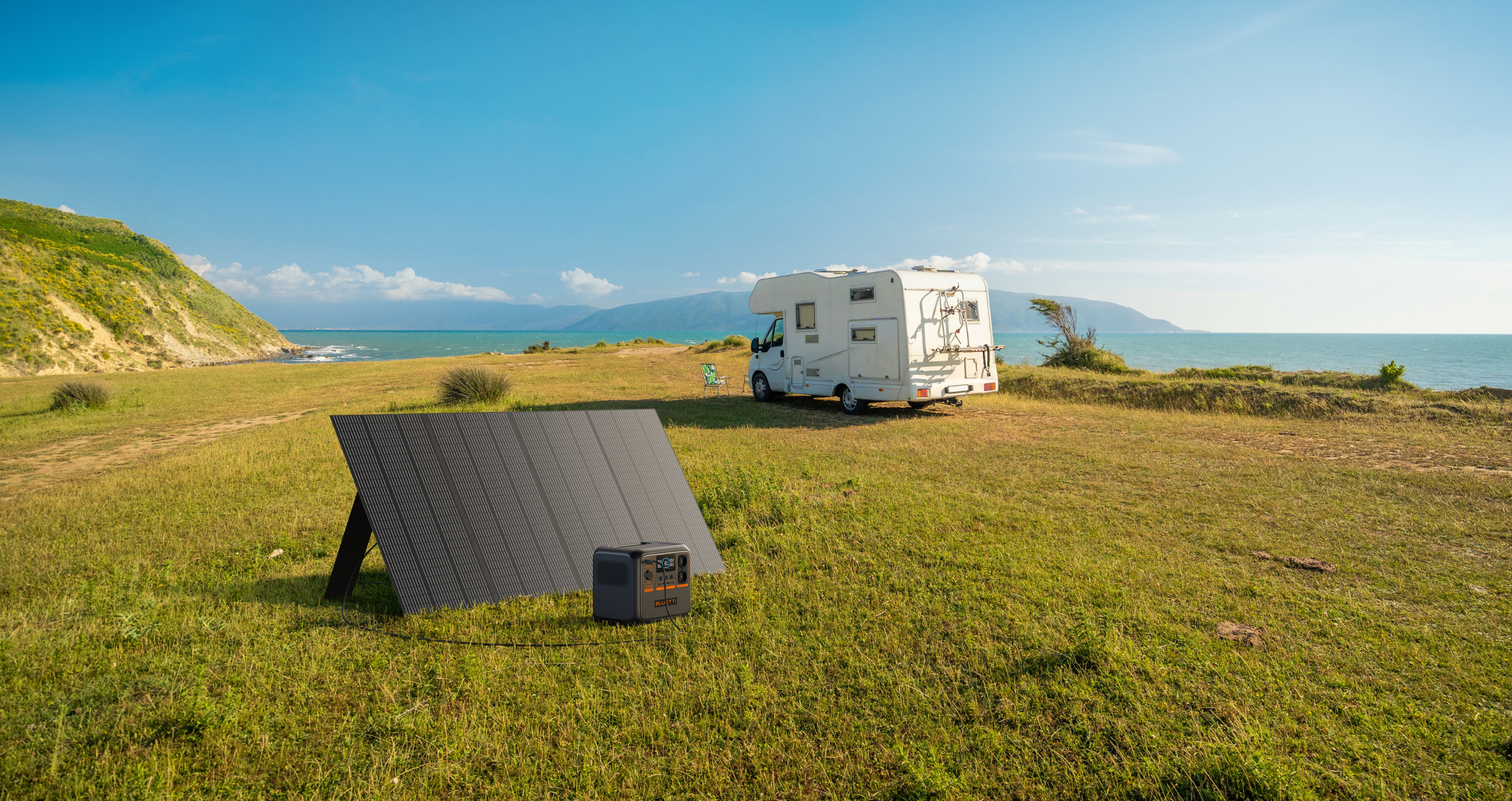Kamper na trawiastym polu w pobliżu morza. Panel słoneczny i stacja zasilania. Słoneczny dzień.