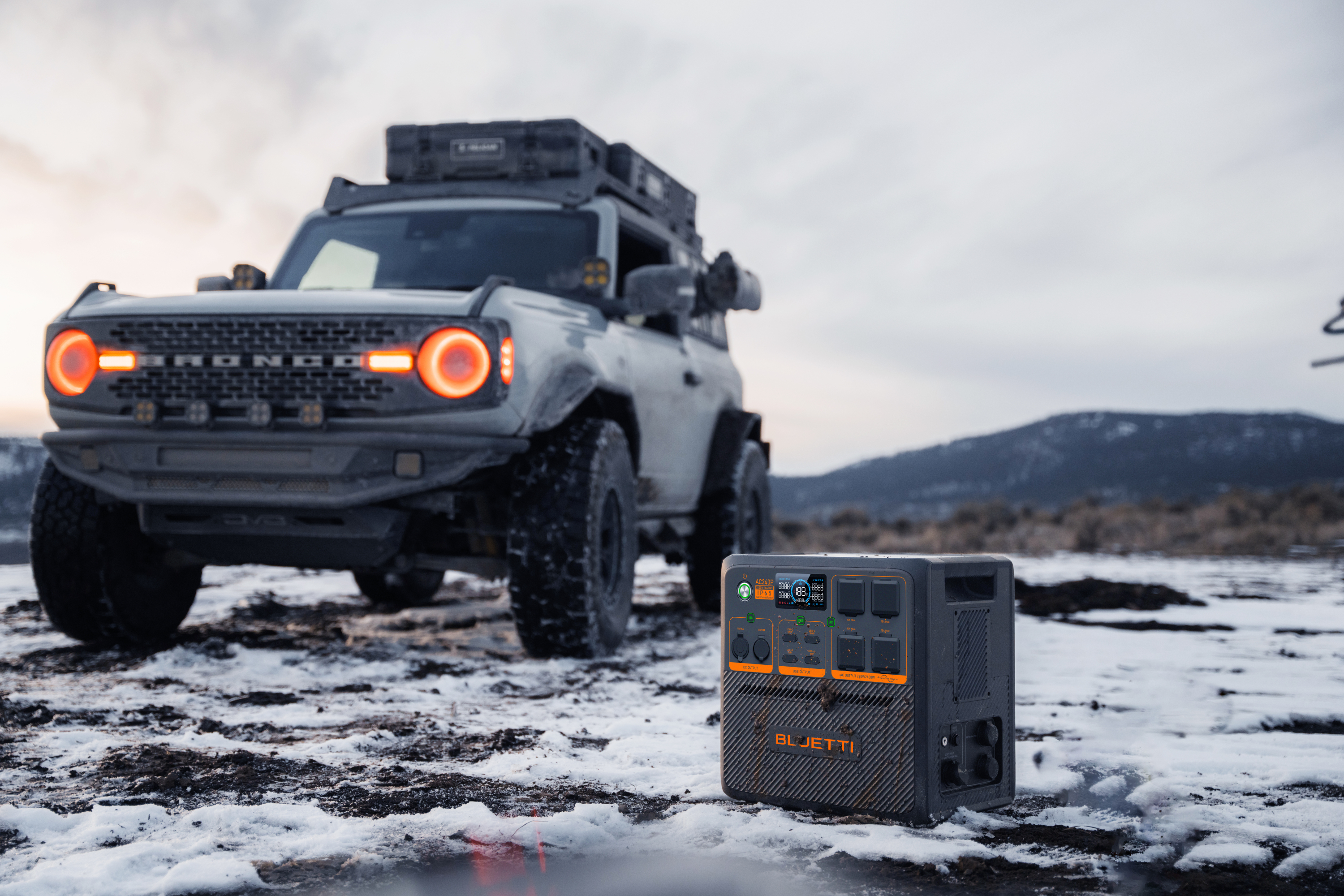 Biały SUV zaparkowany w zaśnieżonym krajobrazie z elektrownią na pierwszym planie.