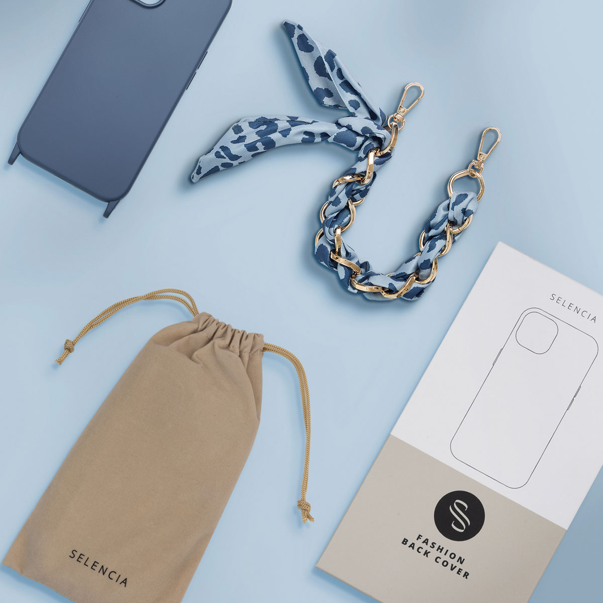 Custodia per telefono, sciarpa, catena e borsa su sfondo azzurro. Scatola con 'Fashion Back Cover'.
