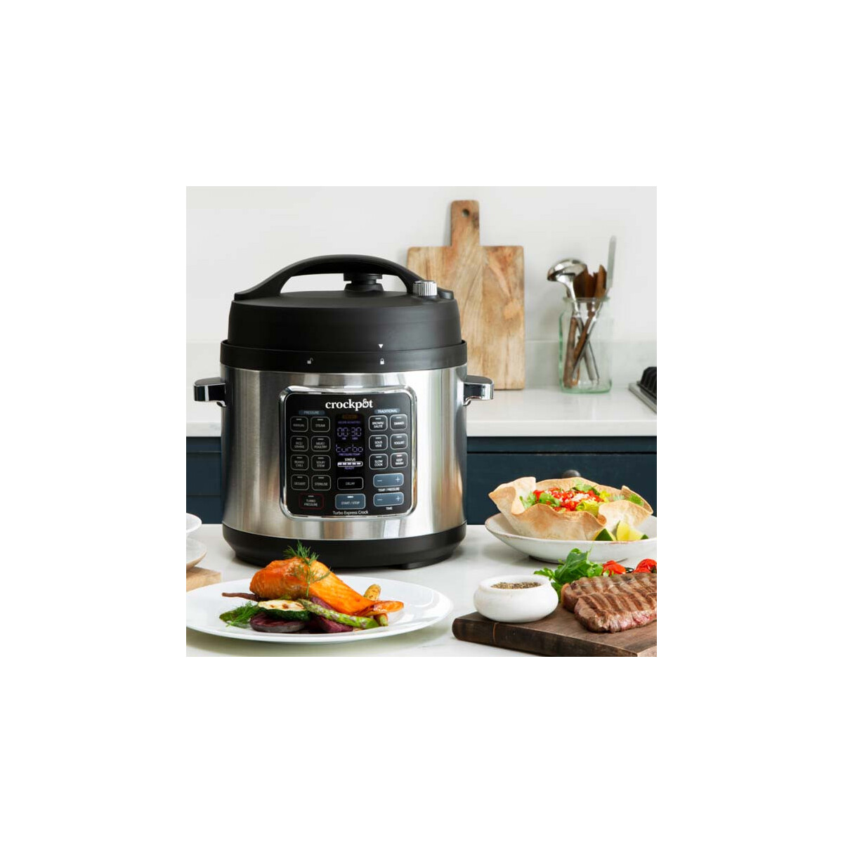 Szybkowar Crock-Pot z jedzeniem na talerzach i deskach do krojenia w kuchni.