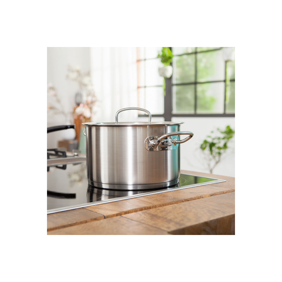 Garnek ze stali nierdzewnej na drewnianej powierzchni w otoczeniu kuchni.