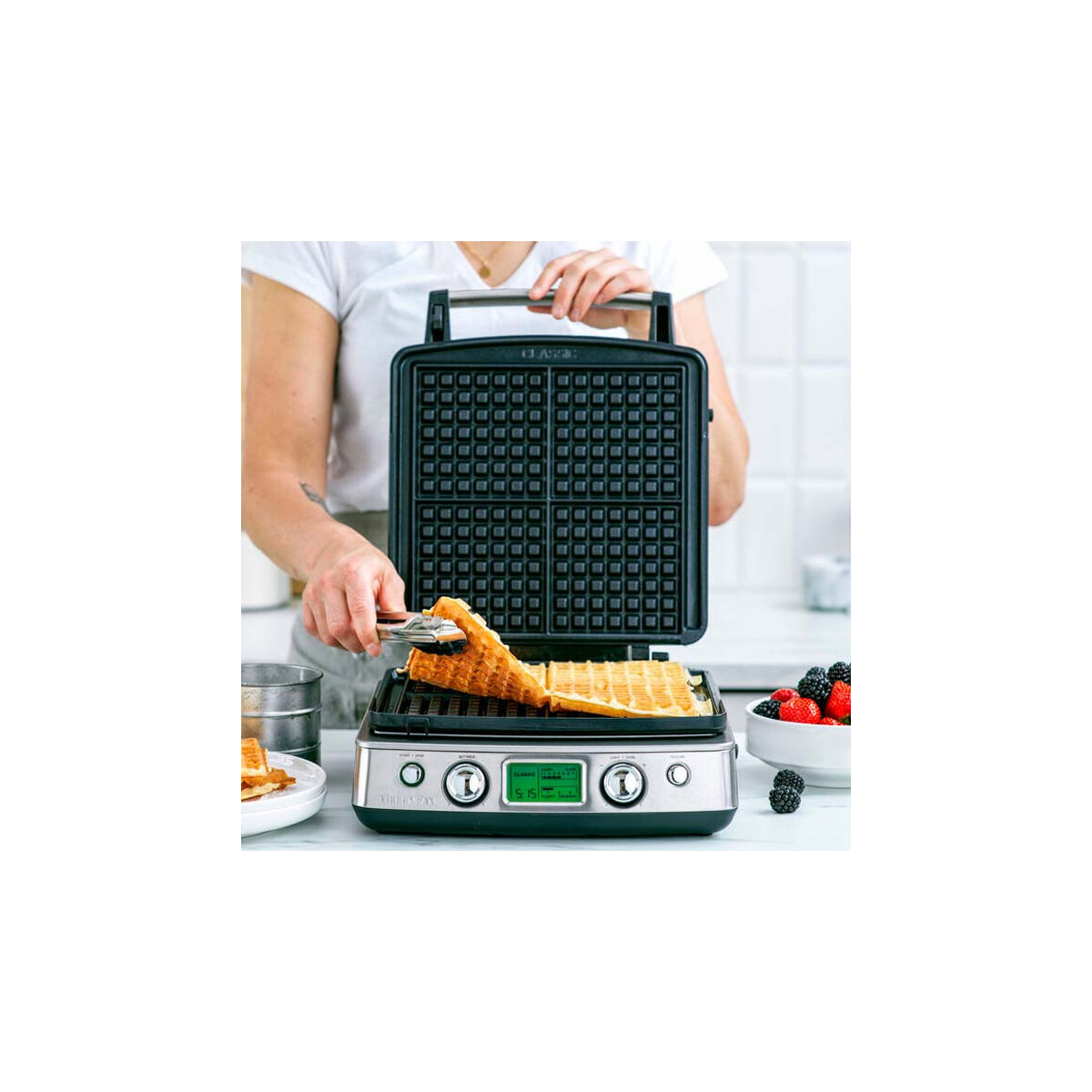 Person verwendet Zangen, um einen Waffel aus einem Waffeleisen zu heben.