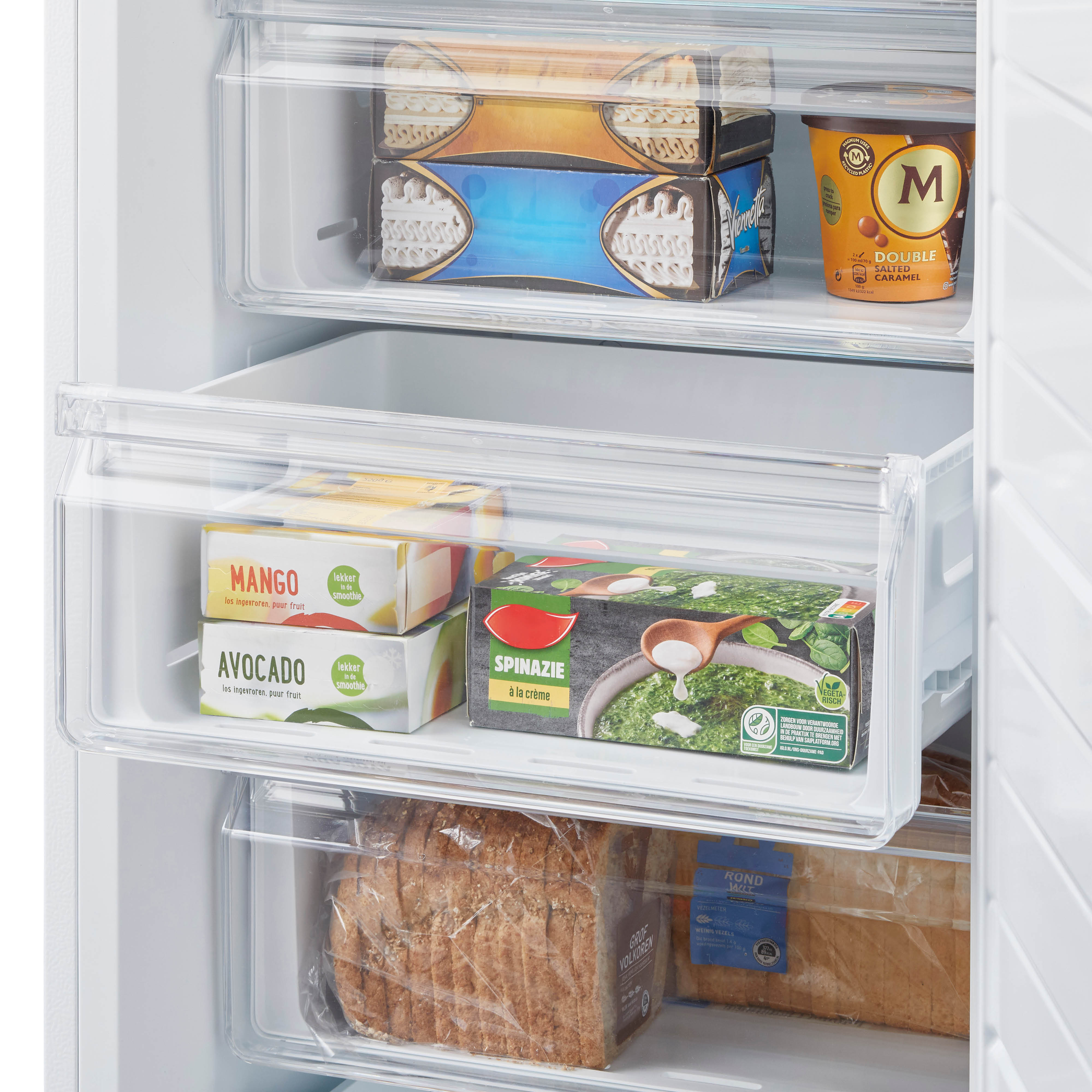 A refrigerator interior with frozen food in drawers. The drawers contain ice cream and vegetables.