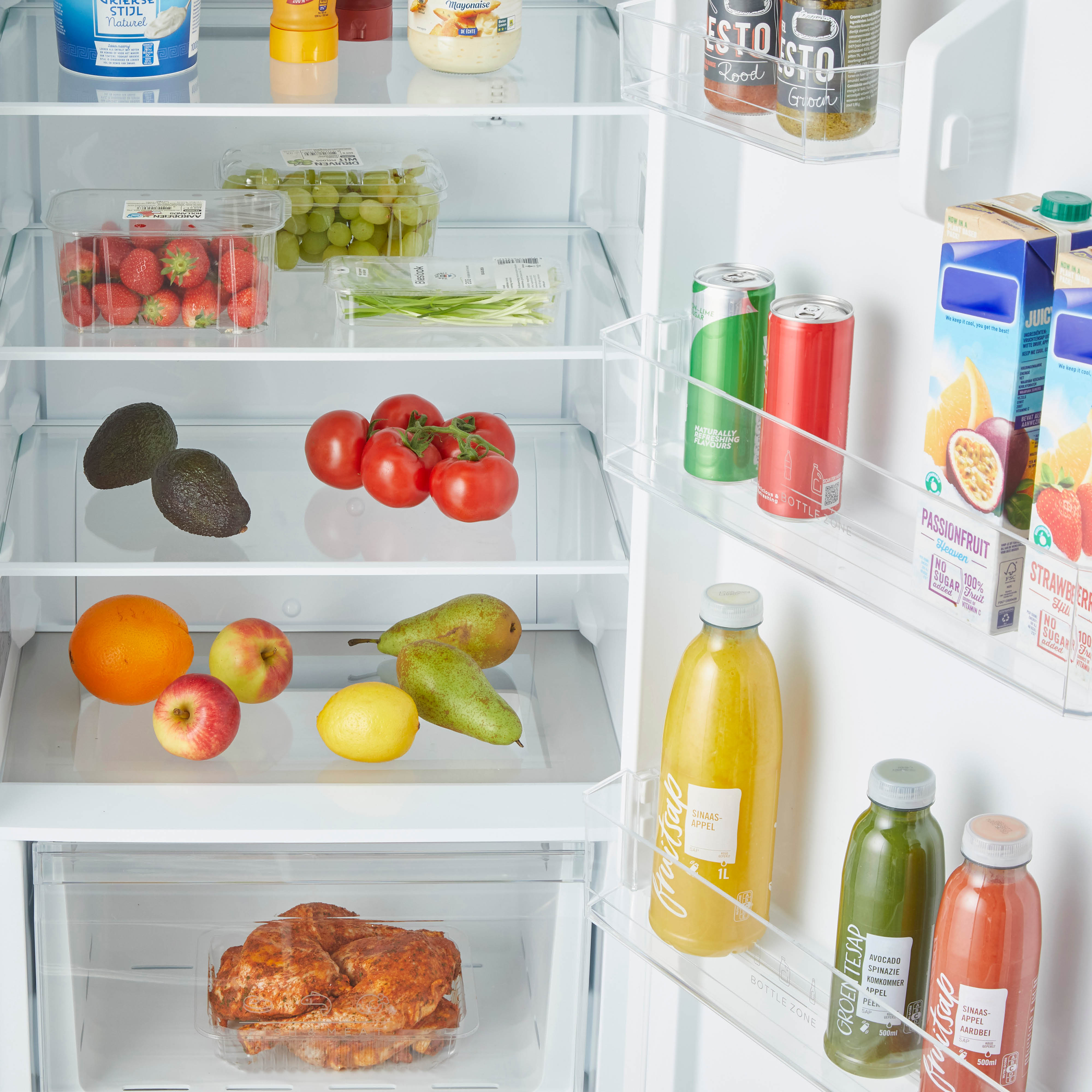 Open koelkast gevuld met eten: fruit, groenten, drankjes en kruiden. De planken zijn helder.