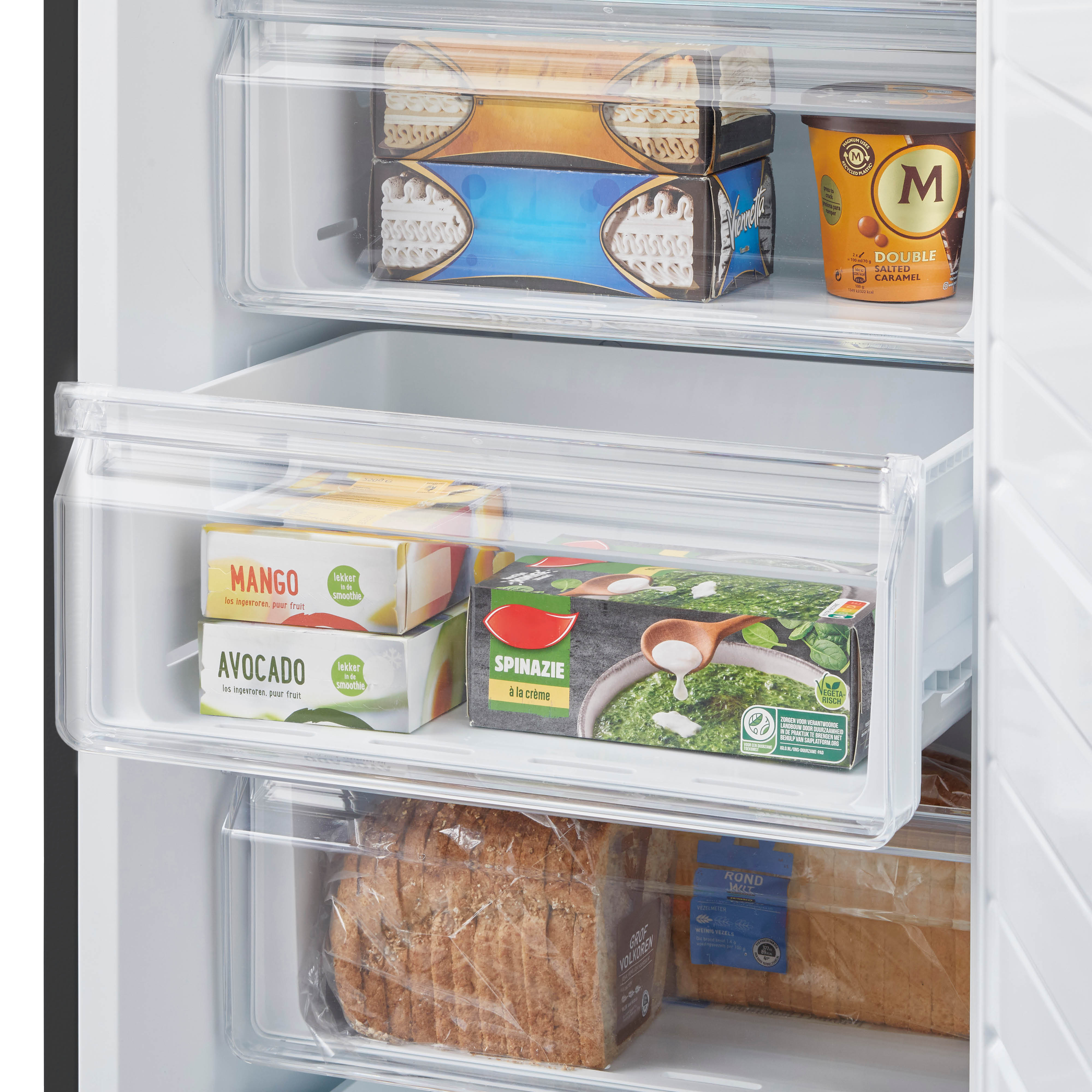 Interior of a fridge with drawers. Ice cream, mango, avocado, and spinach in the drawers.