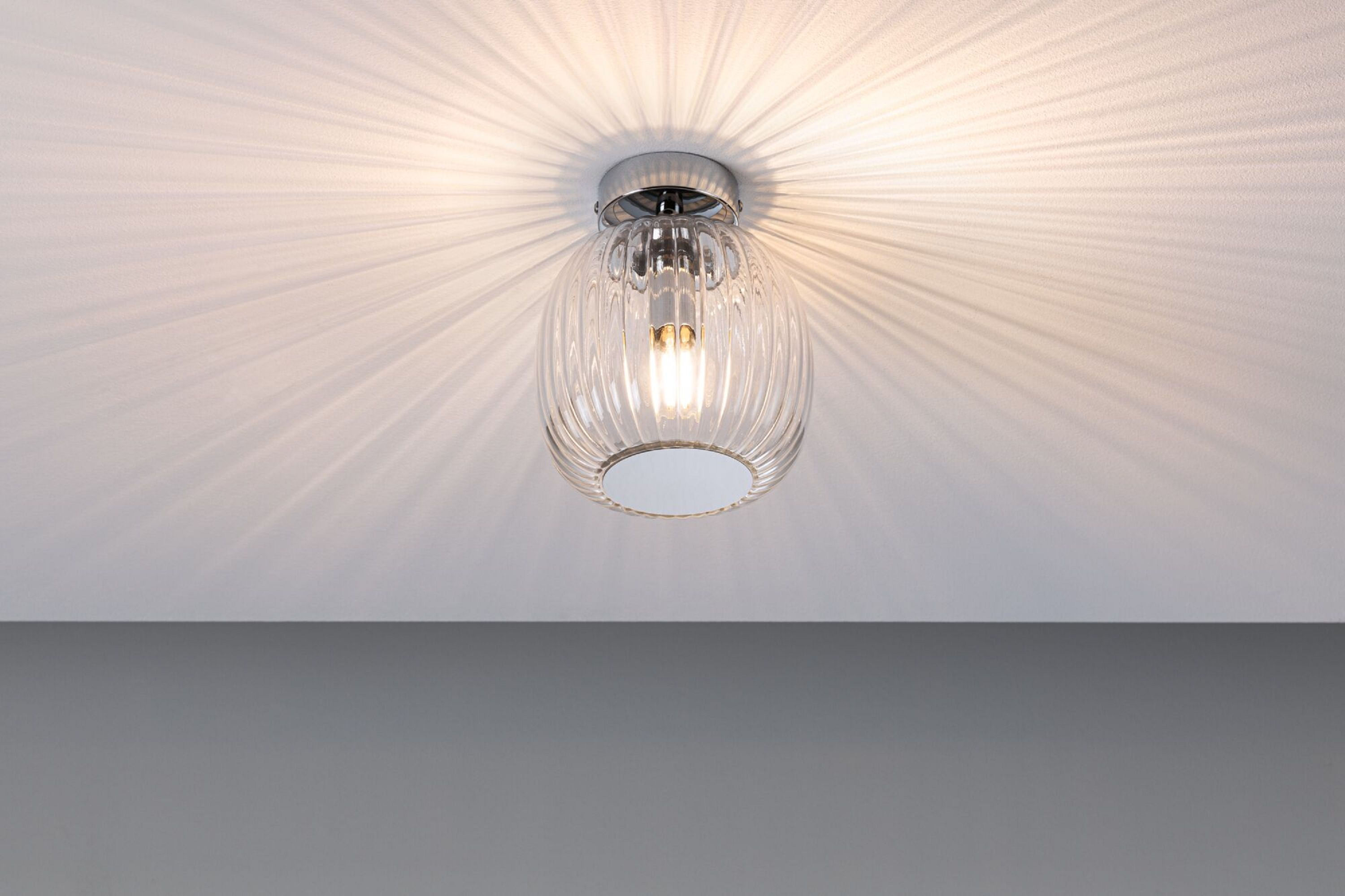 Deckenleuchte mit Glasschirm, die Lichtstrahlen wirft.