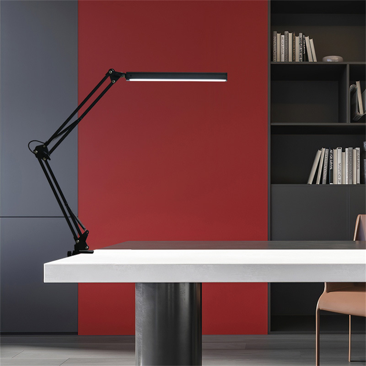 Schwarze, bewegliche Schreibtischlampe mit weißem Schreibtisch und roter Wand. Bücherregal rechts.