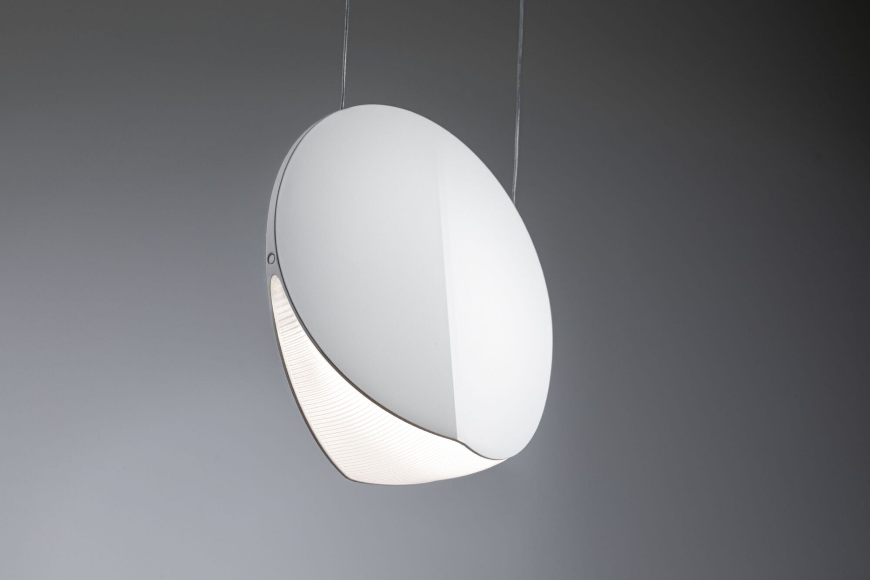 Eine weiße, ovale Lampe, die an einem Draht hängt und von unten weißes Licht ausstrahlt.