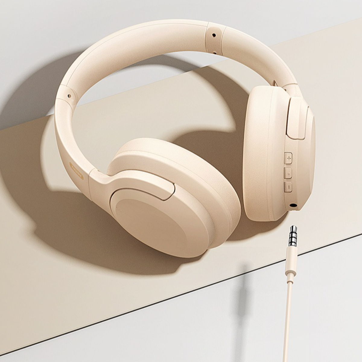 Beige Over-Ear-Kopfhörer mit Spiralkabel und 3,5-mm-Klinkenstecker.