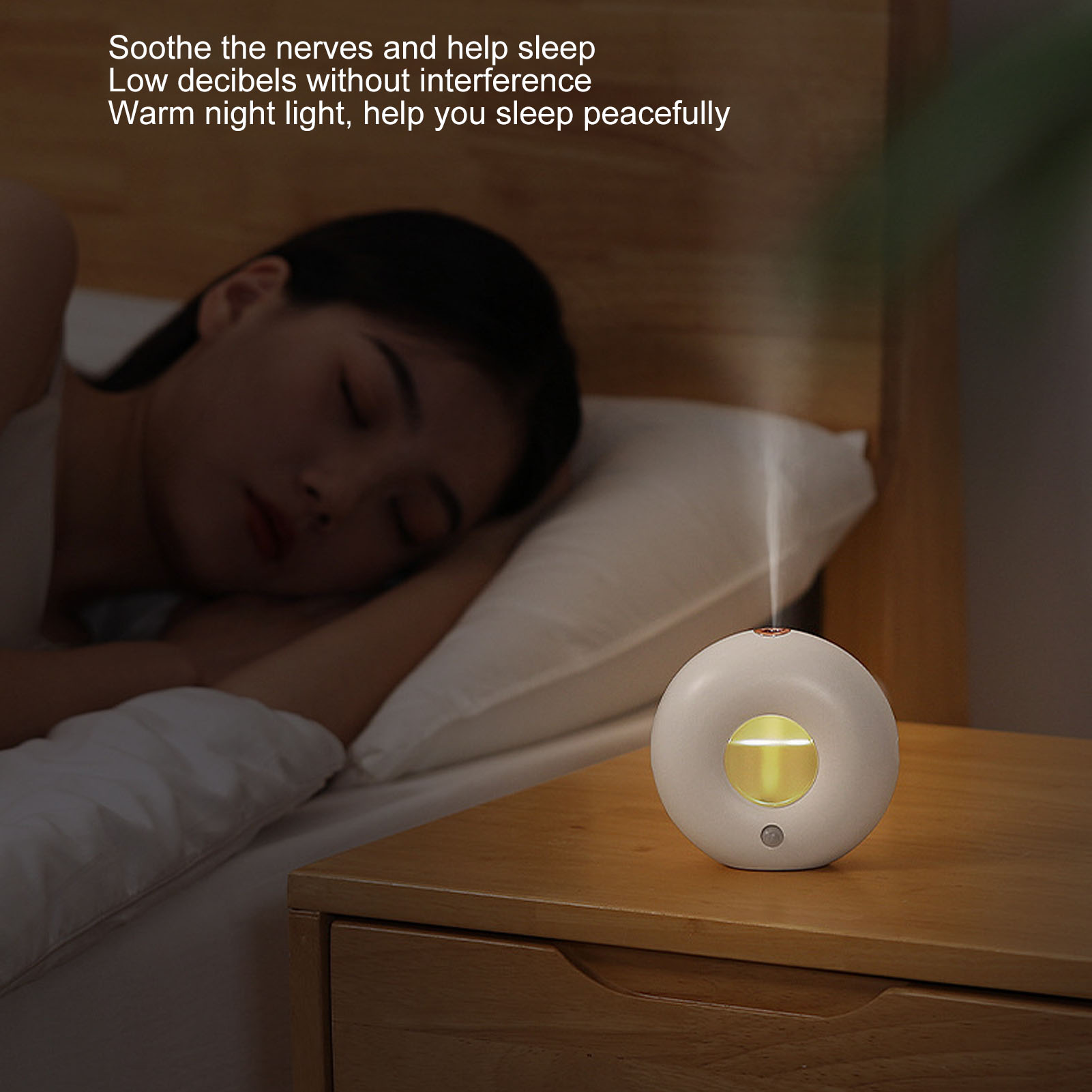 Weißer Aromadiffusor auf einem Nachttisch. Im Hintergrund schläft eine Frau im Bett.