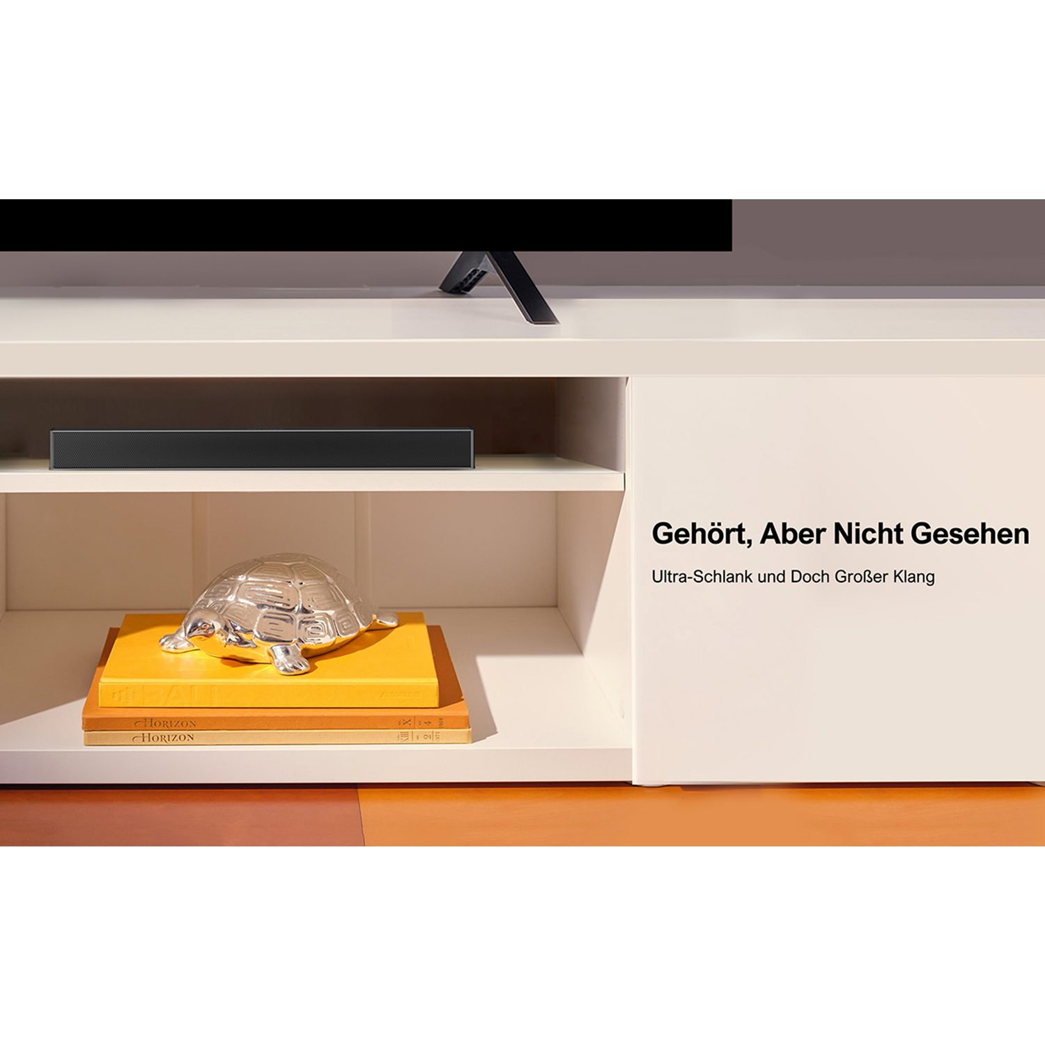 Fernseher auf einem weißen Schrank. Schwarze Soundbar unter dem Fernseher. Bücher und Deko.