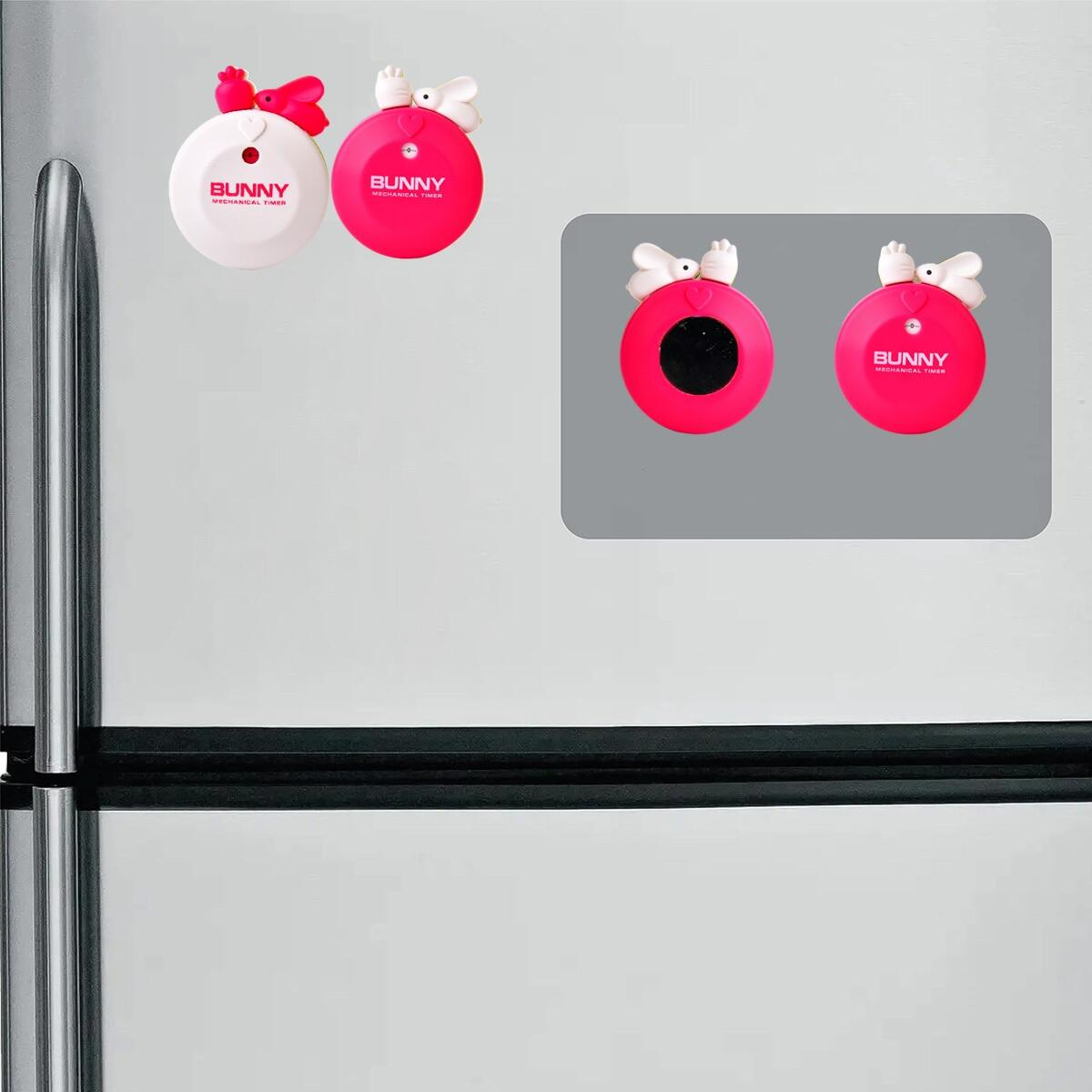 Weiße und rosa Bunny-Timer an einer silbernen Kühlschranktür.