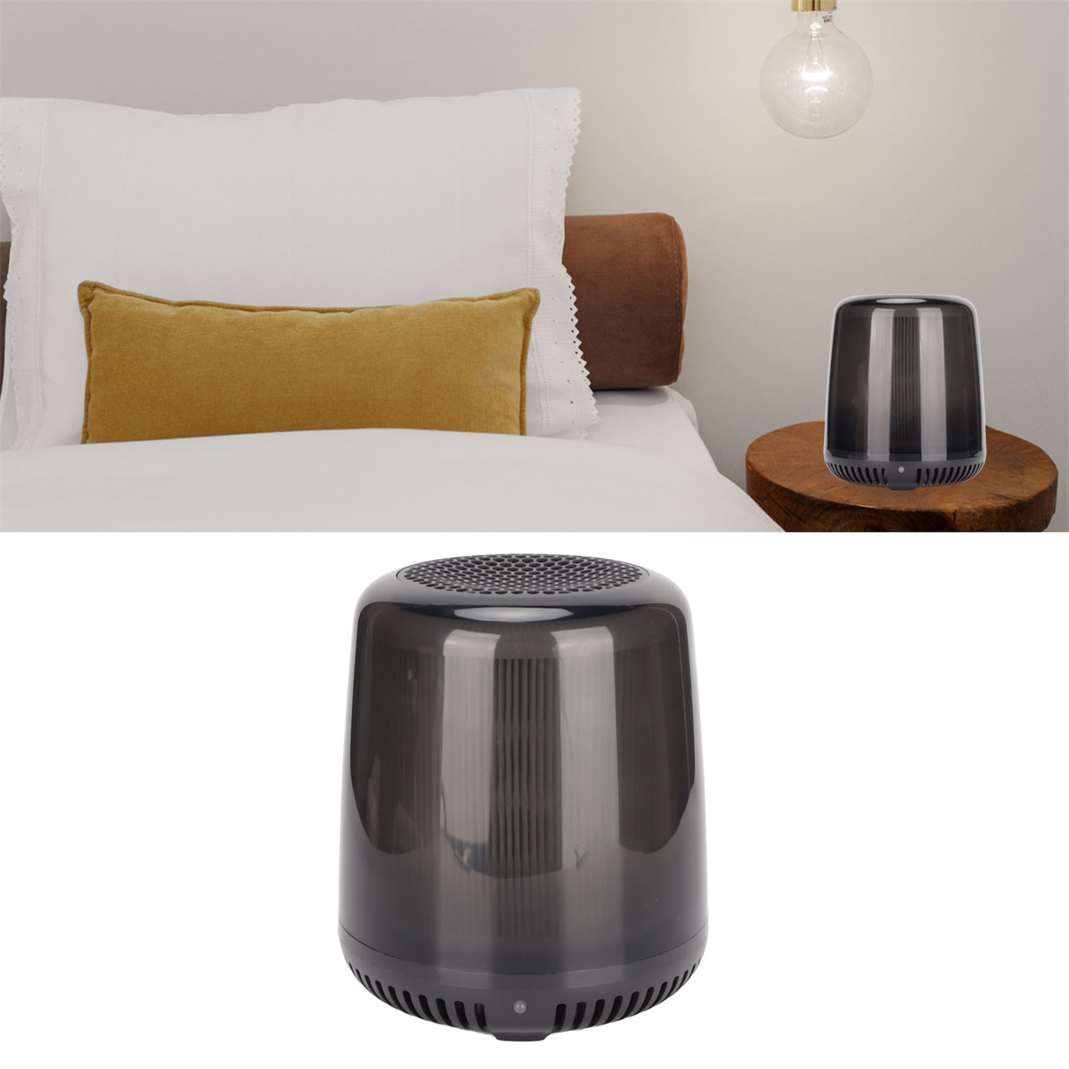 Ein kleiner, schwarzer Lautsprecher steht auf einem Holztisch. Im Hintergrund ein Bett mit Kissen und eine Lampe.